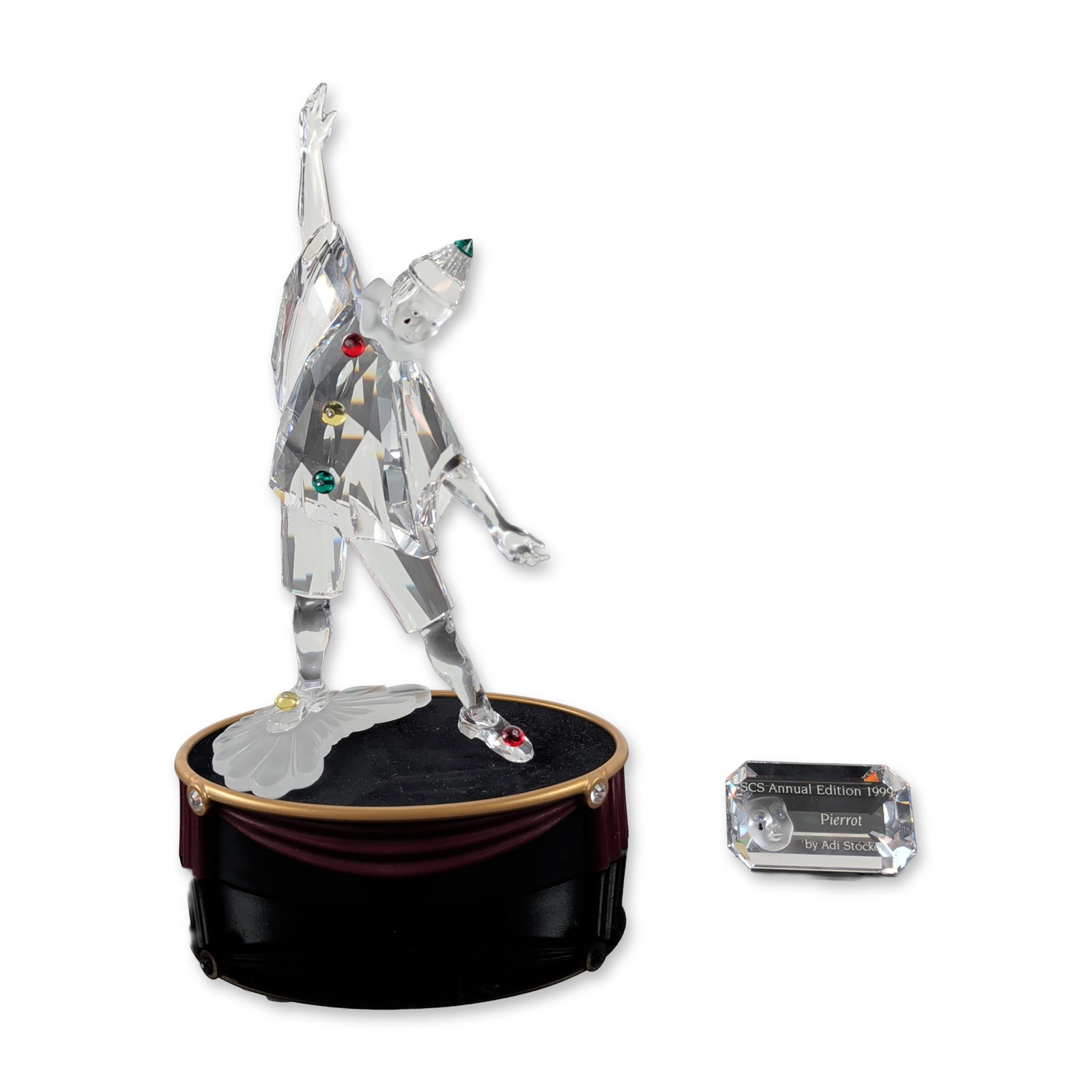 3pc Swarovski 1999 Annual Edition Pierrot Crystal Figurine with Base and Plaque: Swarovski. SCS 1999 Annual Edition Pierrot figurine set in faceted crystal, designed by Adi Stocker as part of the Masquerade trilogy. The figure is depicted in a dynamic pose with one arm extended, f