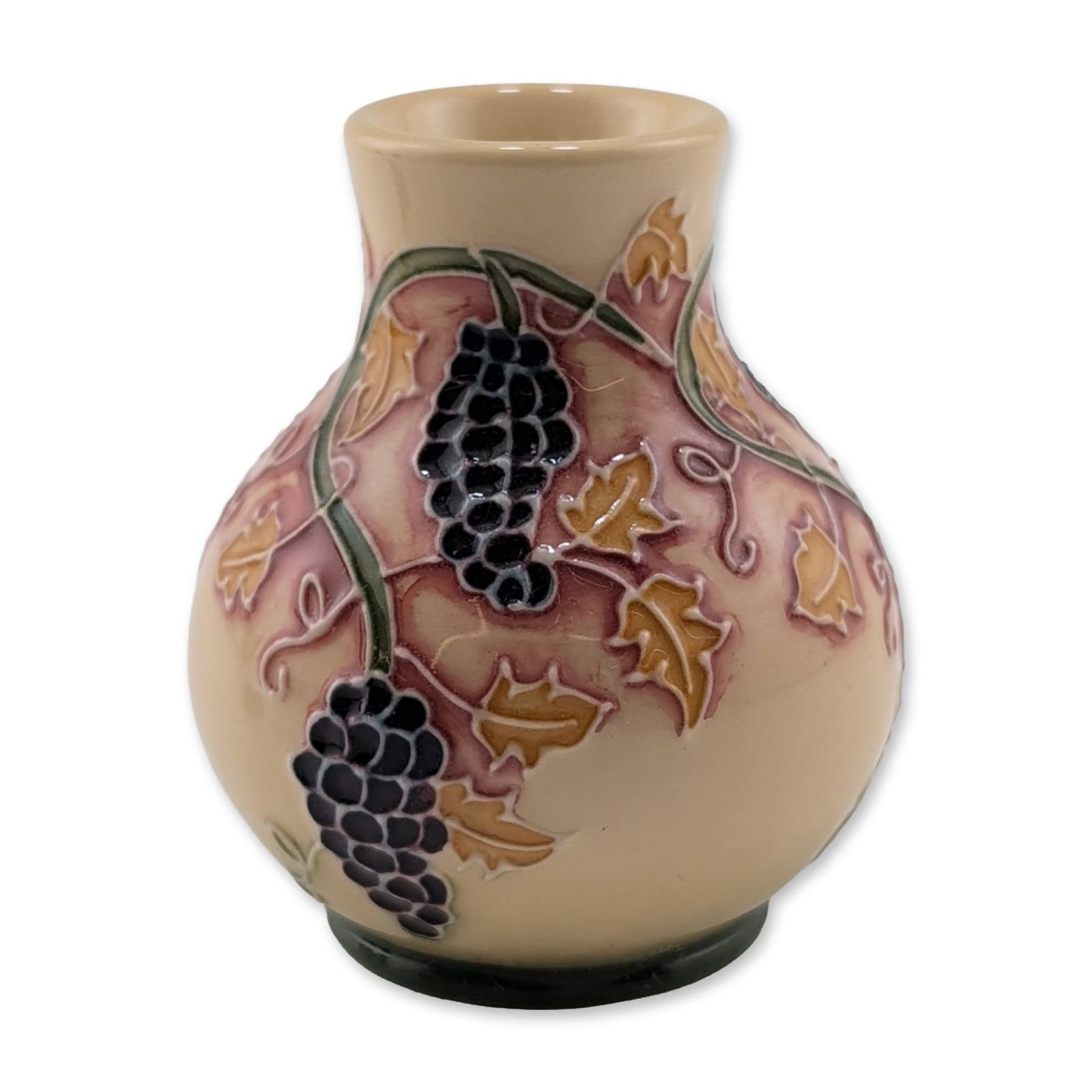 Moorcroft Pottery Miniature Vase, Grapevine: Moorcroft Pottery. Miniature bulbous vase in earthenware, featuring the Grapevine pattern with hand-applied tubelining. The exterior is decorated with clusters of dark purple grapes, ochre-colored lea
