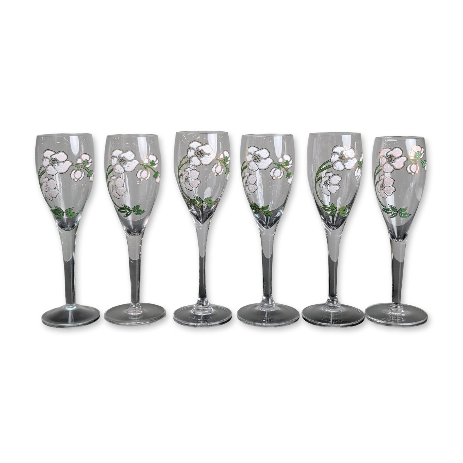 6pc Perrier-Jouet Floral Champagne Flutes: Perrier-Jouet champagne flutes in clear glass featuring the signature Belle Epoque anemone floral motif. Each vessel displays hand-painted five-petaled blossoms in white and pale pink with green folia