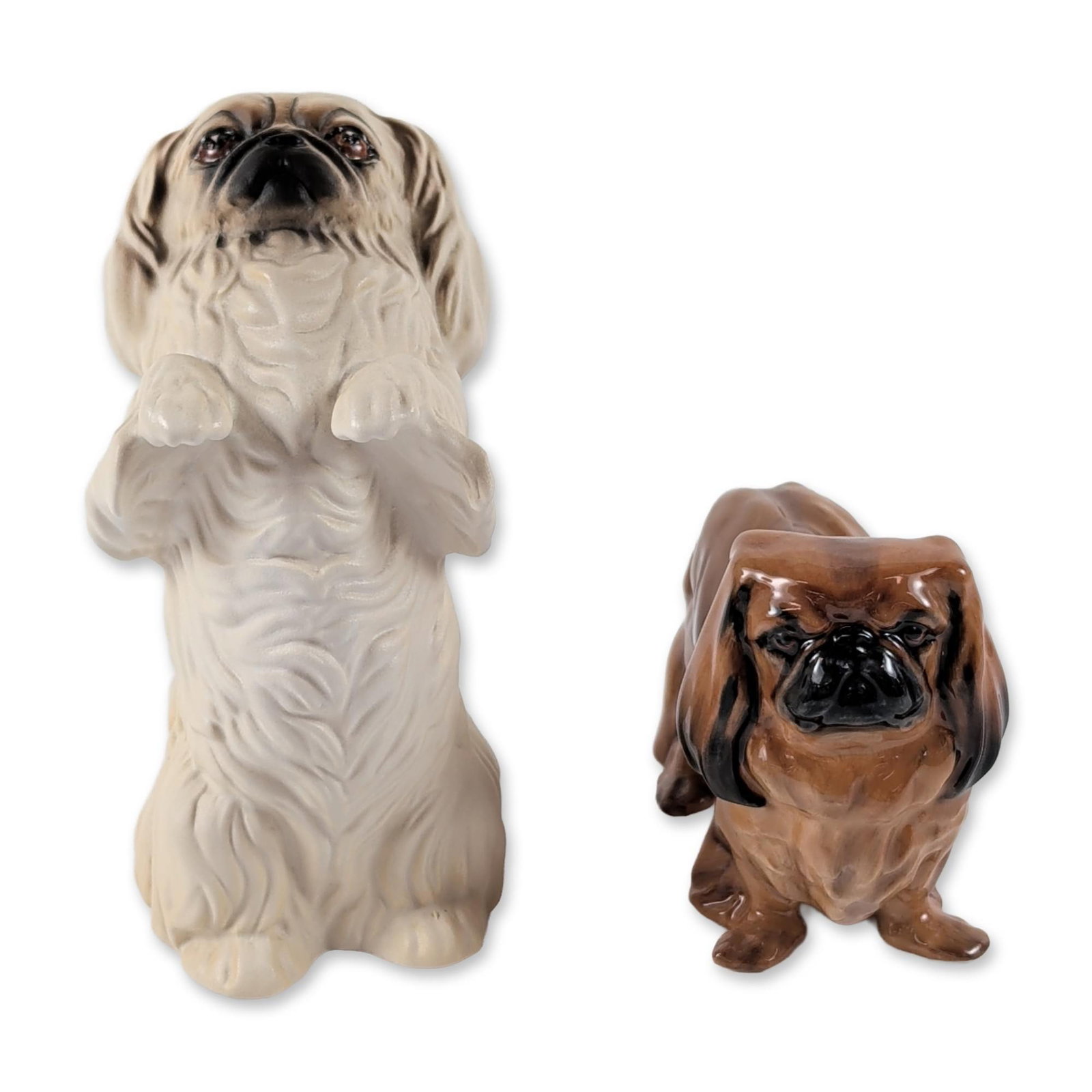 2pc Royal Doulton Bone China Pekingese Figurines: 2pc of Royal Doulton bone china Pekingese dog figurines, one in a charming begging pose and the other standing. The begging piece has a cream matte finish with dark hand-painted facial details and bea