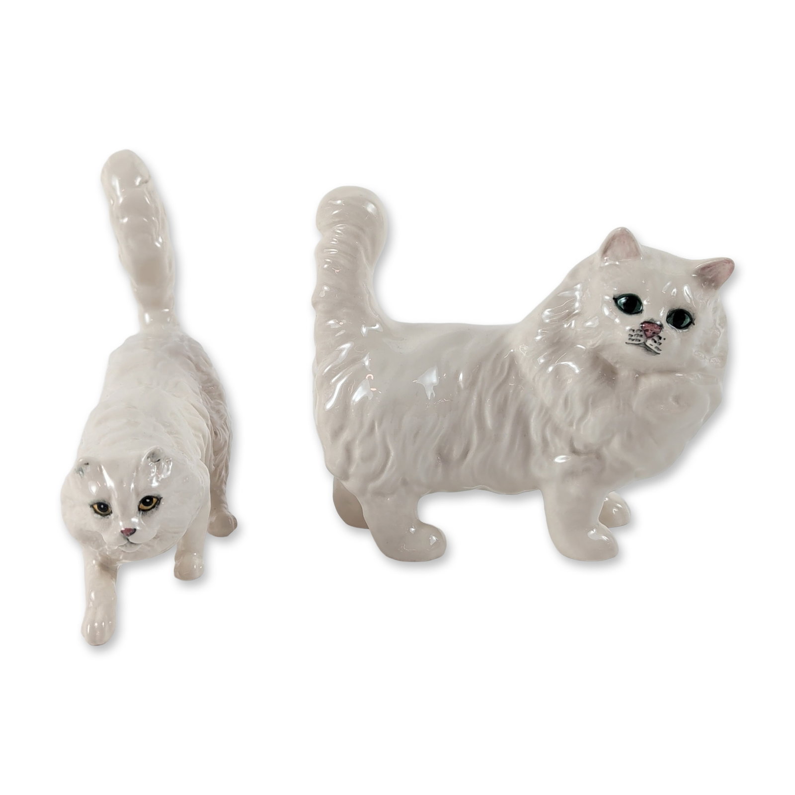 2pc Royal Doulton Porcelain Persian Cat Figurines: Royal Doulton, England. White glazed porcelain cat figurines depicting long-haired Persians. One figure is modeled in a standing pose with an upright tail, while the other is in a crouched inquisitive