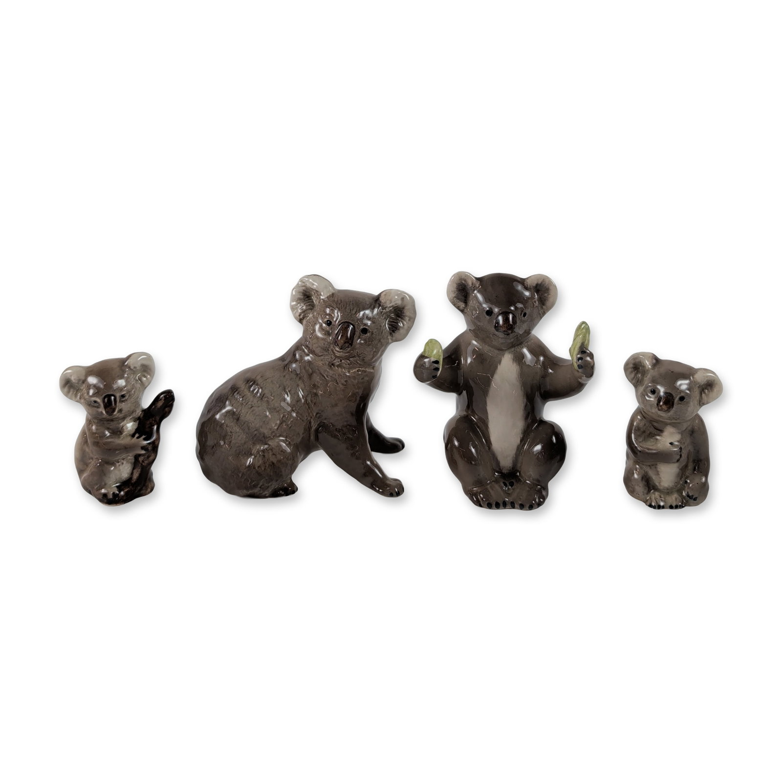 4pc Beswick England Glazed Ceramic Koala Figurines: Beswick, England. Group of four koala figurines in glazed ceramic, depicting the animals in various naturalistic poses. The set includes one large upright figure, one medium-sized figure holding green