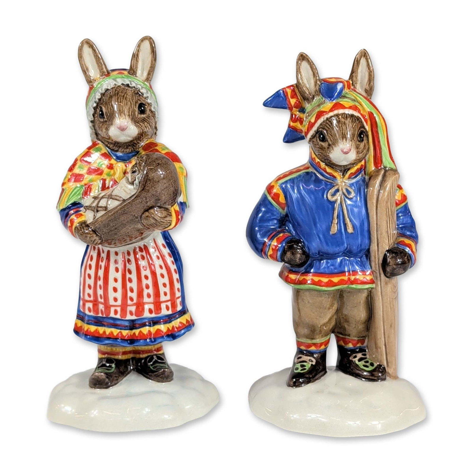 Pair of Royal Doulton Bunnykins Lapland Figurines: Royal Doulton. Pair of glazed ceramic figurines from the Bunnykins collection, featuring traditional Lapland themes. The Winter Lapland figure (DB 297) is depicted in a blue winter tunic with geometri