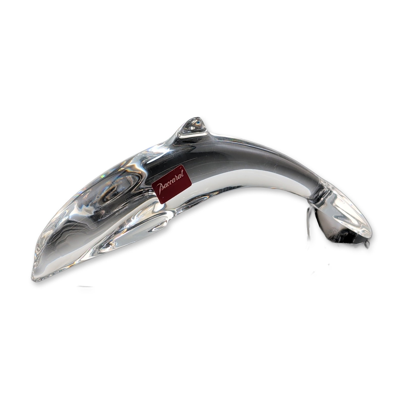 Baccarat France Crystal Dolphin Figurine: Baccarat, France. Travelling Dolphin figurine in clear lead crystal, featuring a stylized arched form resting on a horizontal tail fluke base. The piece retains a red adhesive factory label on the sid