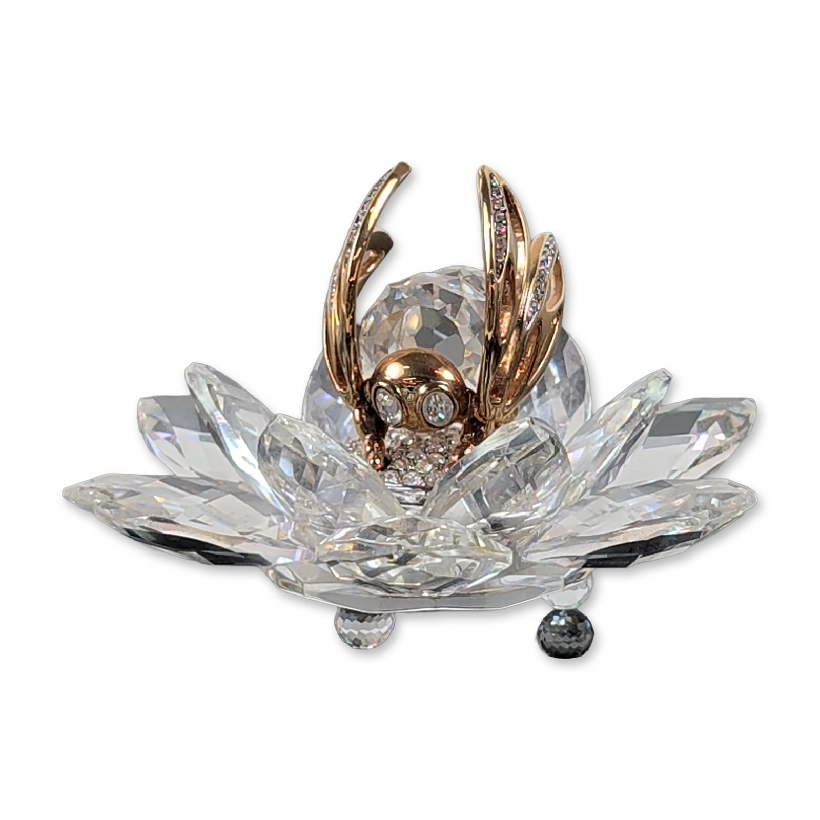 Swarovski Crystal In Flight Series Figurine, Bee - Gold: Swarovski. In Flight figurine in faceted crystal and gold-tone metal, featuring a bee resting on a multi-petaled flower base. The insect is detailed with pave-set clear crystal chatons on the body and