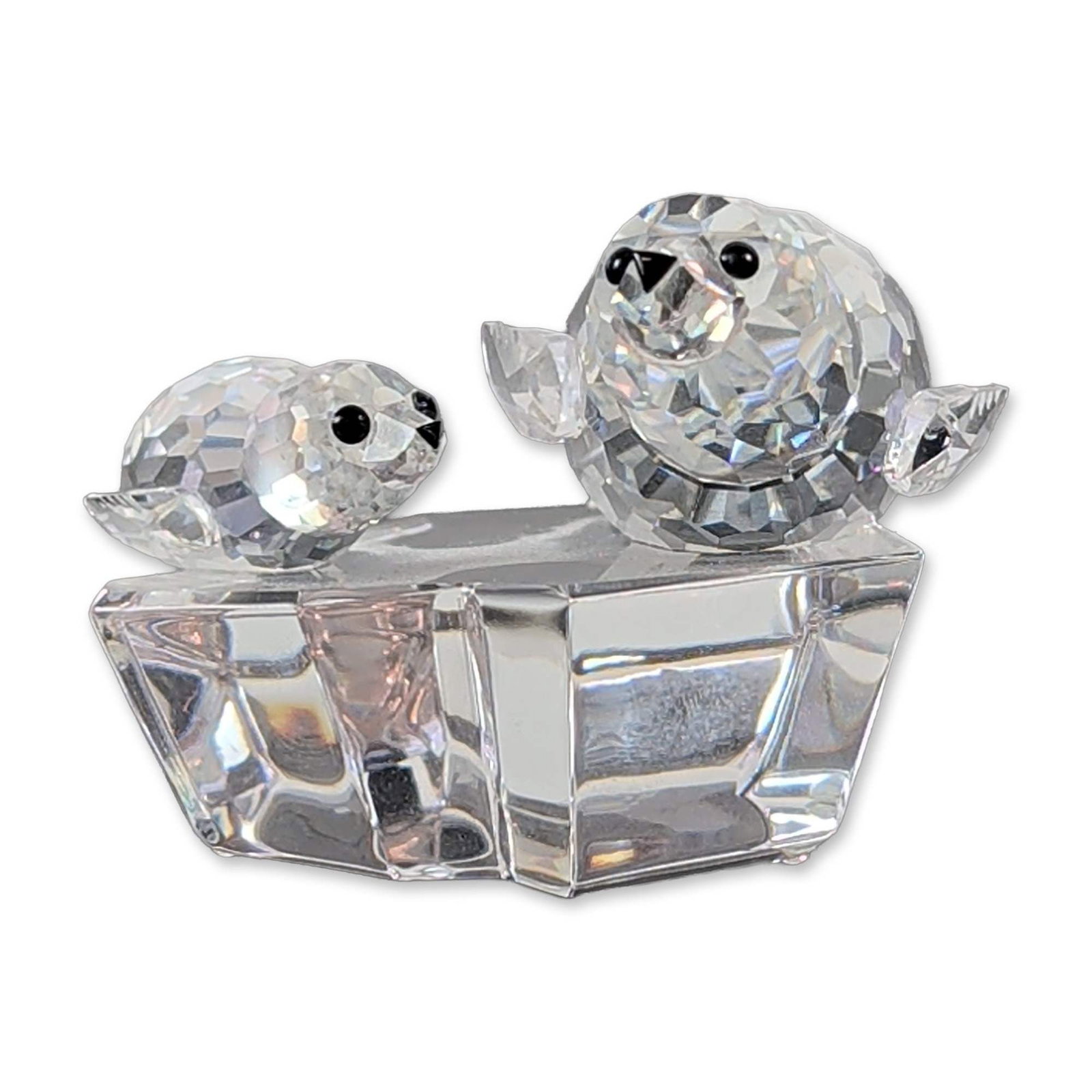 Swarovski SCS 1991 Annual Edition Crystal Figurine, Save Me 158872: This faceted clear crystal piece depicts a mother seal and her pup on an ice floe base. The animals feature small black crystal accents for the eyes and noses. The underside features the acid-etched S