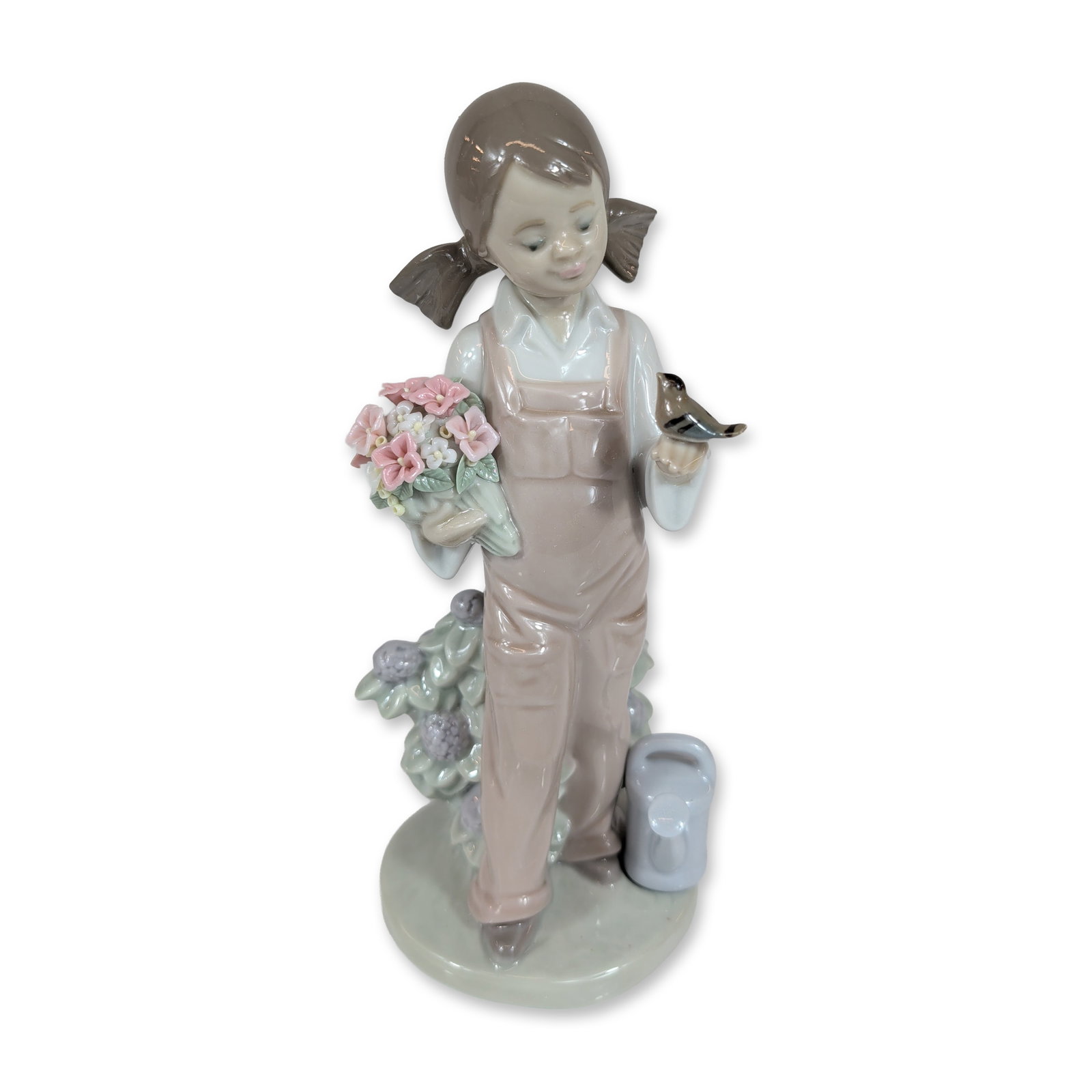 Lladro 5217 Spring Girl Porcelain Figurine: Lladro, Spain. Spring Is Here (model 5217) glazed porcelain figurine, designed by sculptor Juan Huerta. The figure depicts a young girl in mauve overalls and a white shirt with pigtails, holding a bou