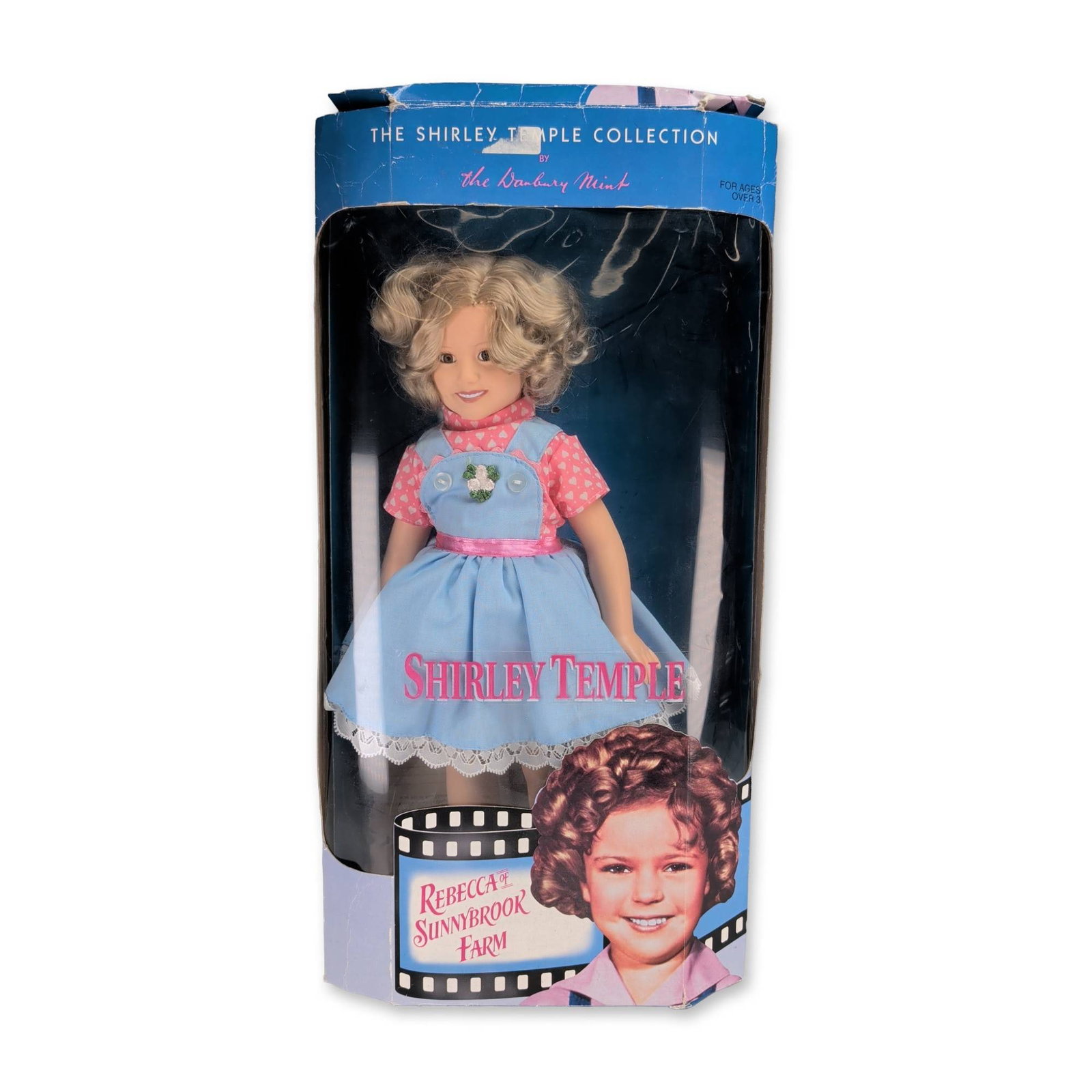 Danbury Mint Shirley Temple Rebecca Doll: Danbury Mint. Fourteen-inch collector doll from The Shirley Temple Collection, representing the character Rebecca from the 1938 film Rebecca of Sunnybrook Farm. Features a bisque porcelain head, hands