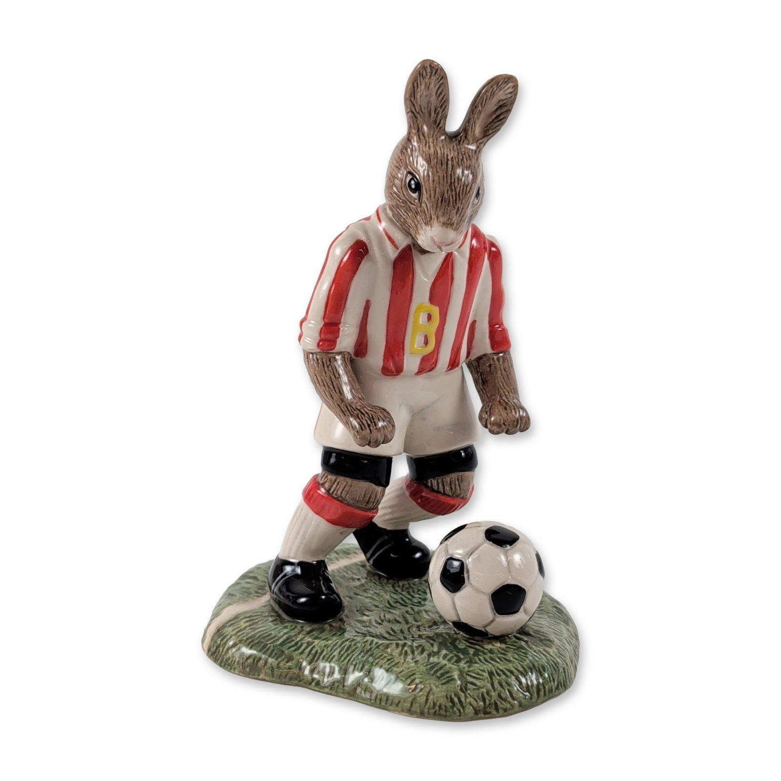 Royal Doulton Bunnykins He Shoots He Scores Figurine: Royal Doulton. Ceramic figurine from The Pastimes Collection, titled He Shoots, He Scores (DB 425). The hand-decorated rabbit character is dressed in a red and white striped soccer jersey with a yello