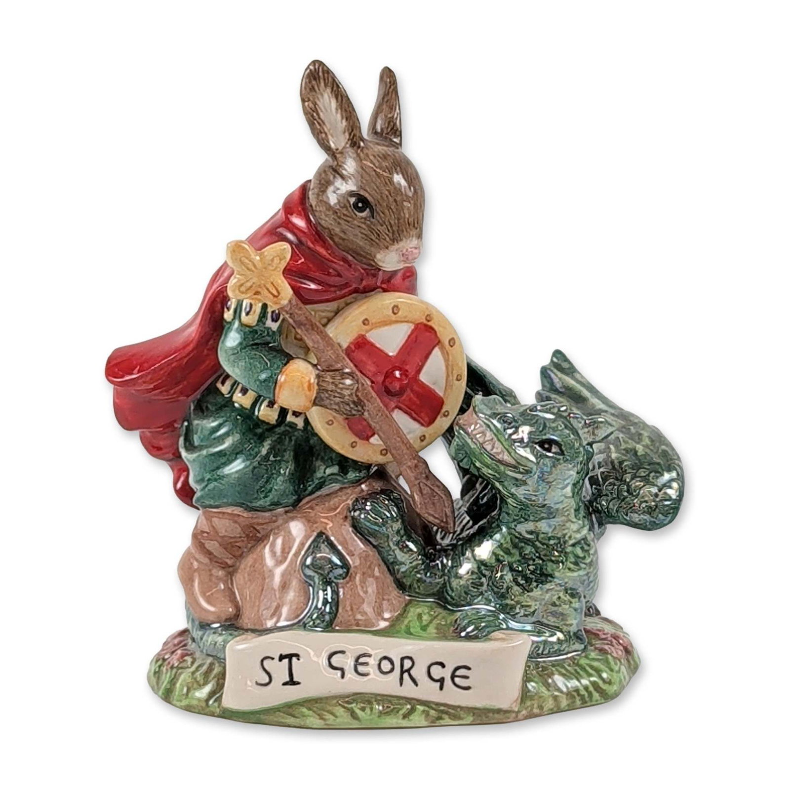 Royal Doulton Bunnykins Saint George Ceramic Figurine: Royal Doulton glazed polychrome ceramic figurine from the Bunnykins Patron Saints Collection, model DB 398, titled St. George. The figurine depicts a rabbit dressed in a green tunic and red cloak as a