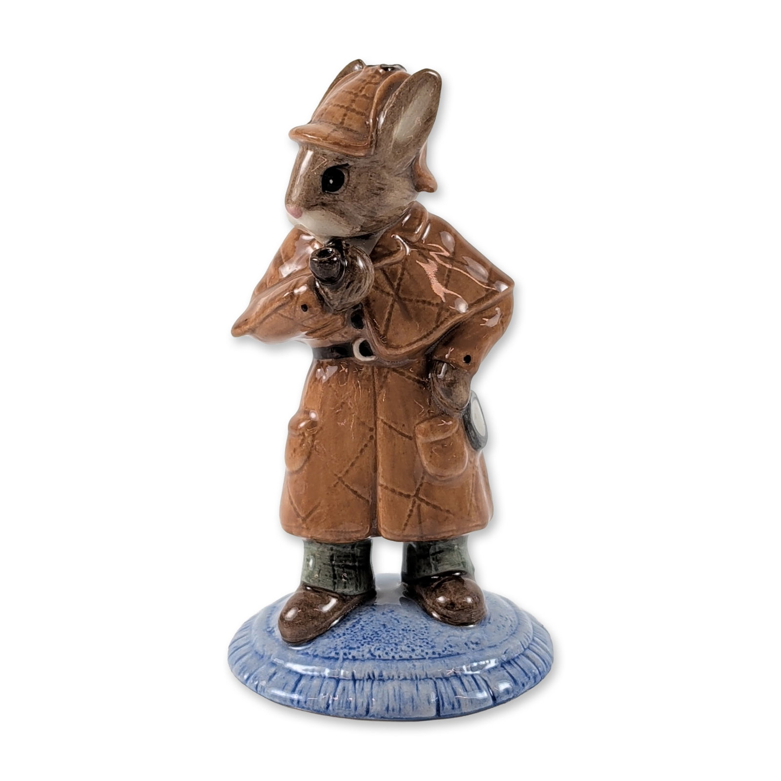 Royal Doulton Detective Bunnykins DB193 Figurine: Royal Doulton glazed ceramic figurine, Detective Bunnykins model DB 193. The figure depicts a rabbit character in a brown quilted deerstalker hat and Inverness cape, holding a magnifying glass and a p