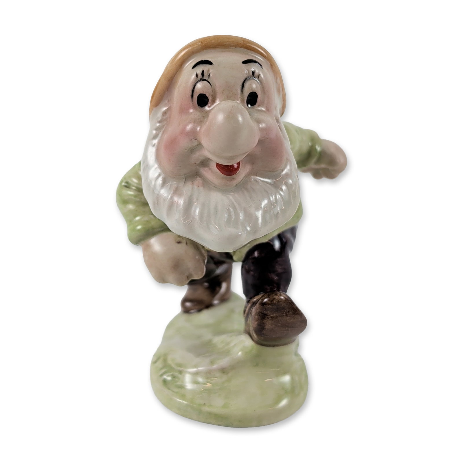 Beswick Disney Sneezy Glazed Ceramic Figurine: Beswick, England. Glazed ceramic figurine depicting the character Sneezy from Walt Disney's 1937 animated film Snow White and the Seven Dwarfs. The figure is modeled in a dynamic pose wearing a pale g