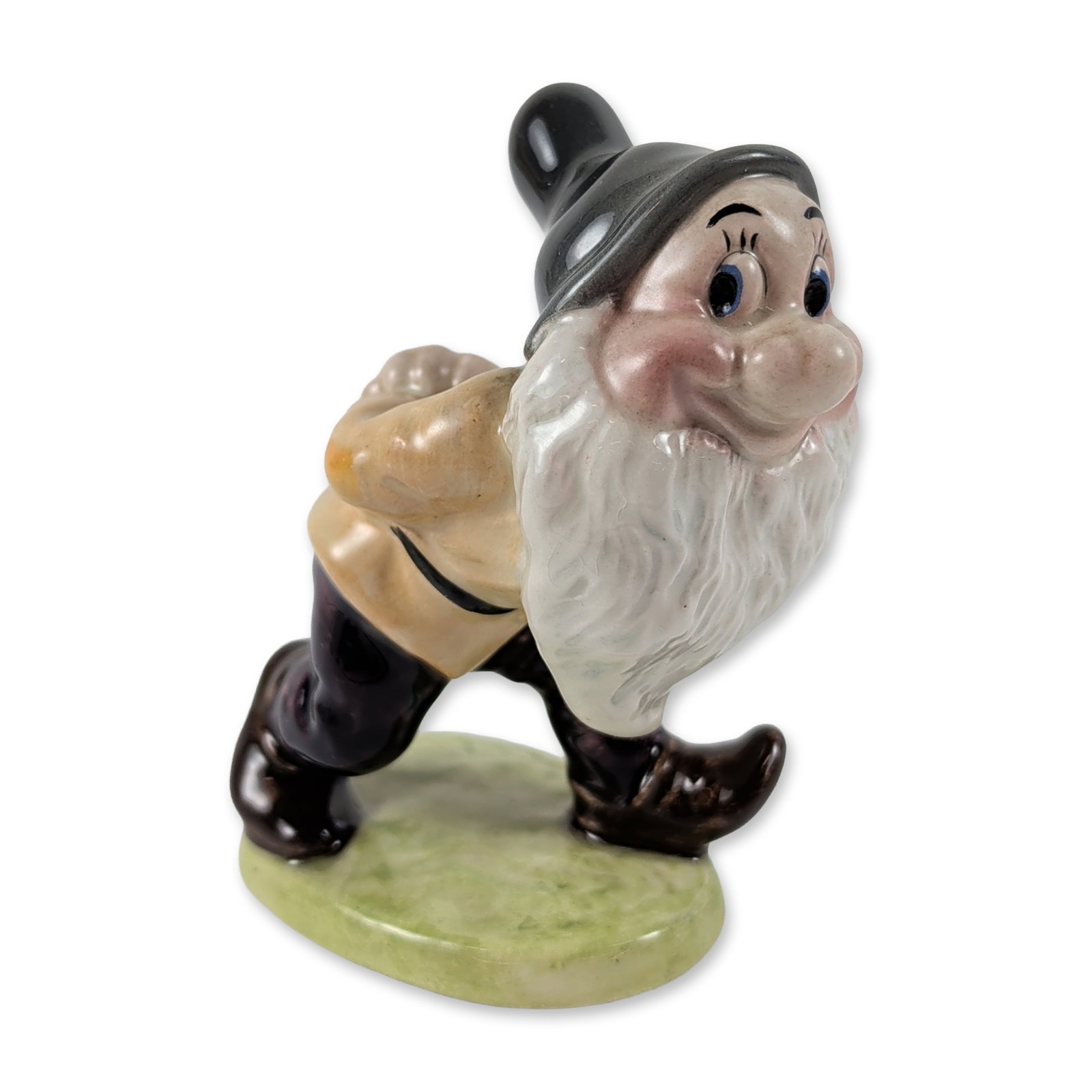 Beswick Walt Disney Bashful Ceramic Figurine: Beswick, England. Glazed ceramic figurine of Bashful from Walt Disney's Snow White and the Seven Dwarfs, model number 1327. The figure is depicted in a shy pose with hands clasped behind the back, wea