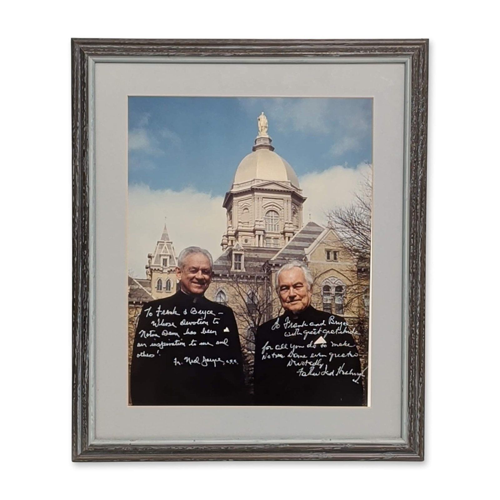 Notre Dame University Fathers Hesburgh and Joyce Photograph, Framed: Framed and matted photograph featuring Reverend Theodore Hesburgh, C.S.C. and Reverend Edmund "Ned" Joyce, C.S.C. posed before the University of Notre Dame Main Building and Golden Dome. The photograp