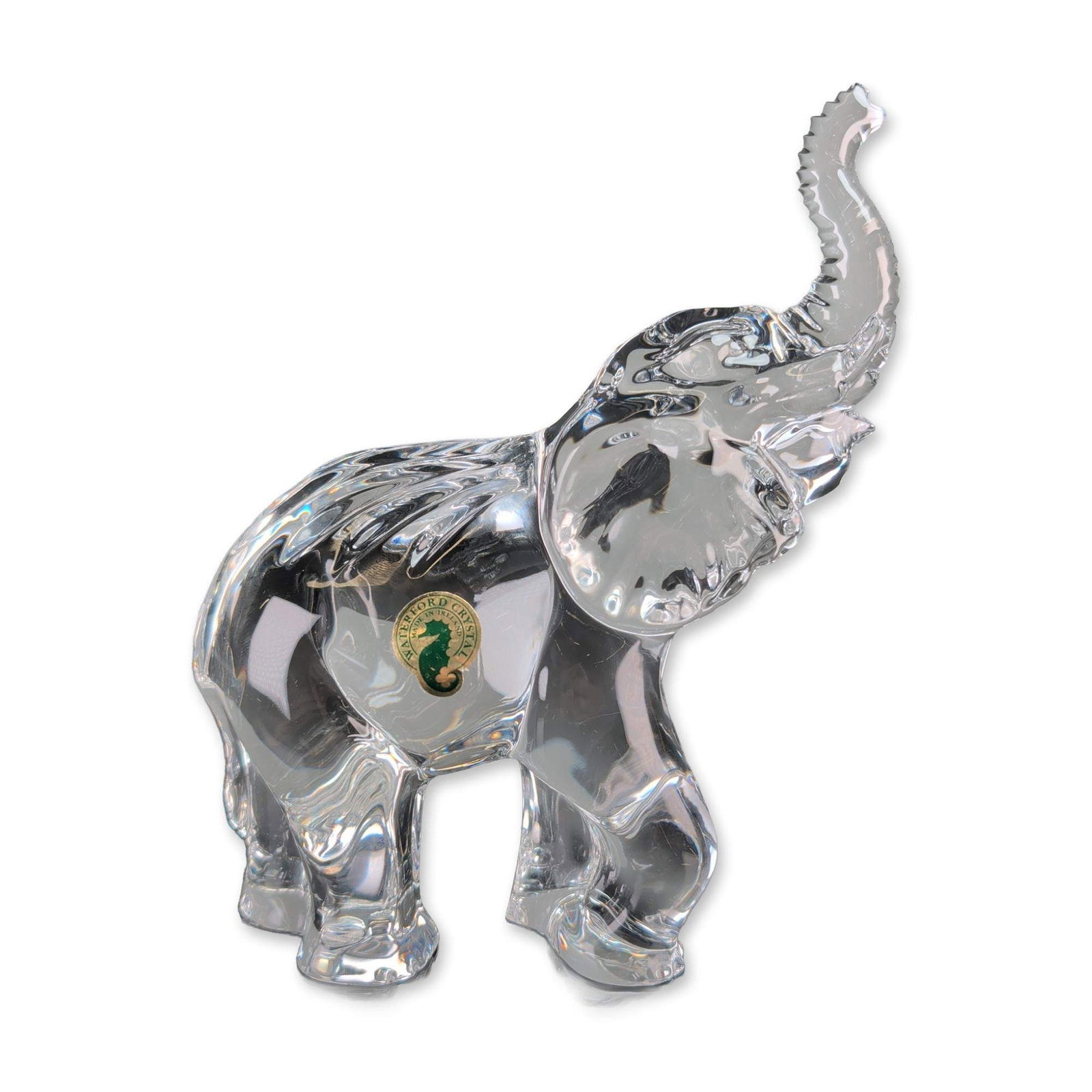 Waterford Crystal Elephant Figurine: Waterford crystal elephant figurine. Sculpted clear lead crystal form featuring an elephant with its trunk raised in a traditional good luck pose. The piece exhibits a dynamic, forward-leaning stance 