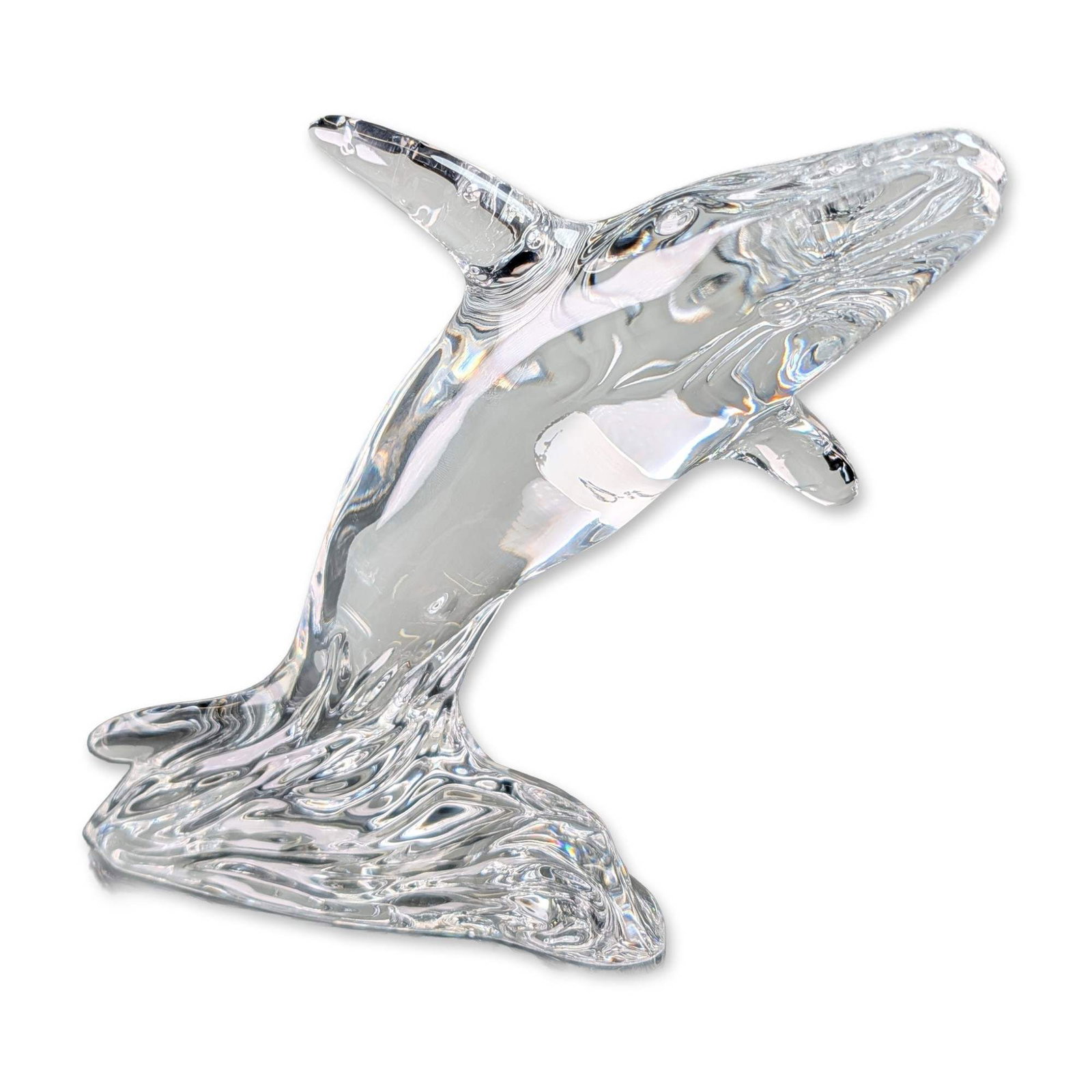 Waterford Crystal Whale Figurine: Waterford Crystal lead crystal figurine depicting a breaching humpback whale rising from a textured wave base. The model features horizontal ridges on the underbelly and elongated pectoral fins. Acid-
