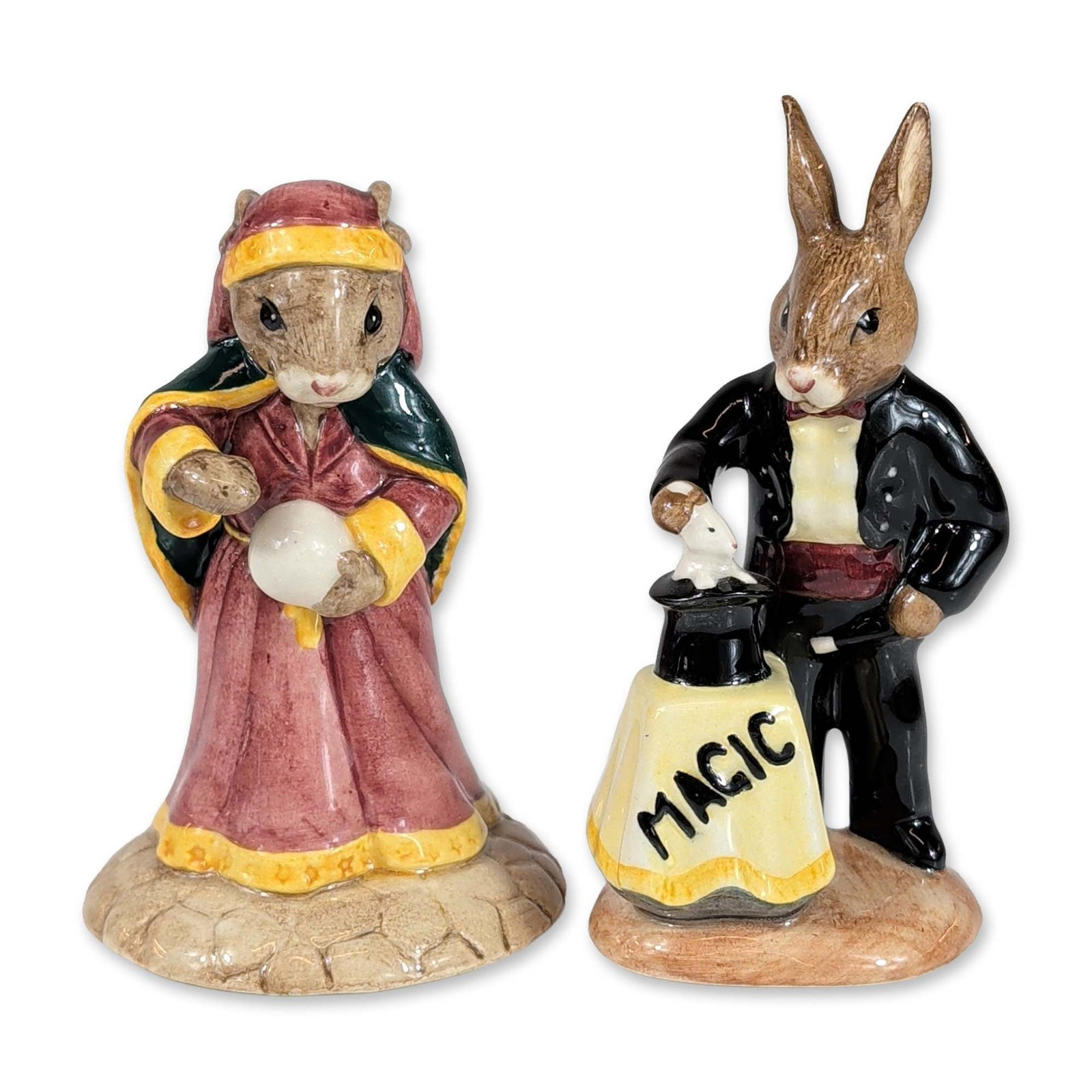 Royal Doulton Bunnykins Magician and Fortune Teller Figurines: Royal Doulton. Pair of hand-painted glazed porcelain figurines from the Bunnykins series, featuring Magician (DB 126) and Fortune Teller (DB 218). The Magician figure is modeled in a black tuxedo with