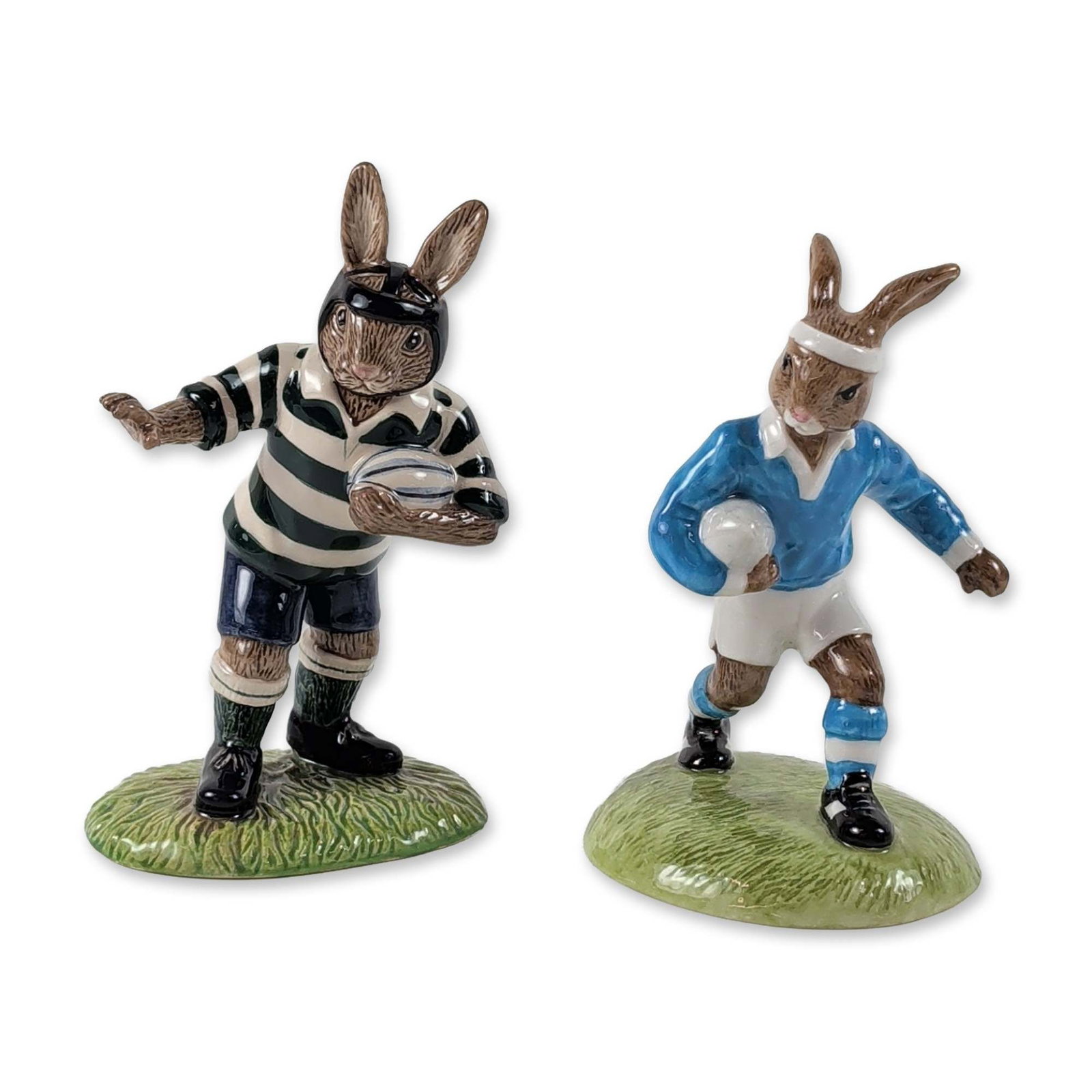 2pc Royal Doulton Bunnykins Rugby Figurines: Royal Doulton. Pair of ceramic Bunnykins figurines depicting rugby matches. The first figure, titled "Rugby Player" (DB 318), shows a rabbit in a blue jersey numbered 15 with white shorts and a headba