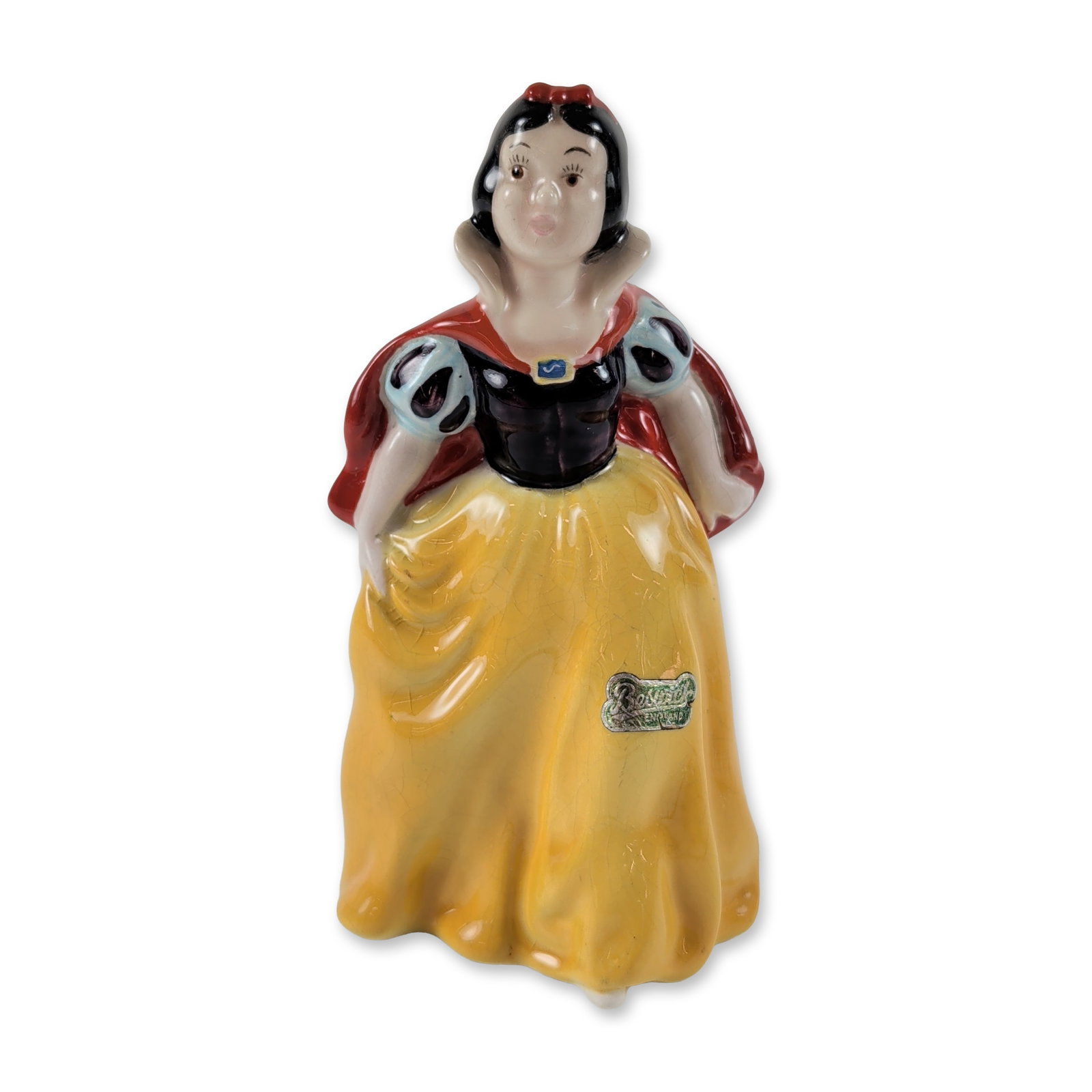 Beswick Walt Disney Snow White Figurine: Beswick glazed ceramic figure depicting Disney's Snow White, styled in a yellow skirt, blue bodice with light blue slashed sleeves, high standing collar, and red cape. Base features incised model