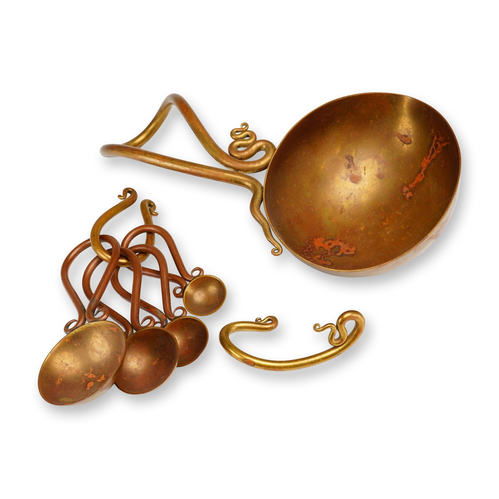 A Joe Spoon Signed Brass Set of Measuring Spoons and Cup: This set of hand-wrought brass kitchenware is the work of artist metalsmith Joe Spoon. The collection includes a set of measuring spoons secured by a brass ring, a large ladle or measuring cup, and a 