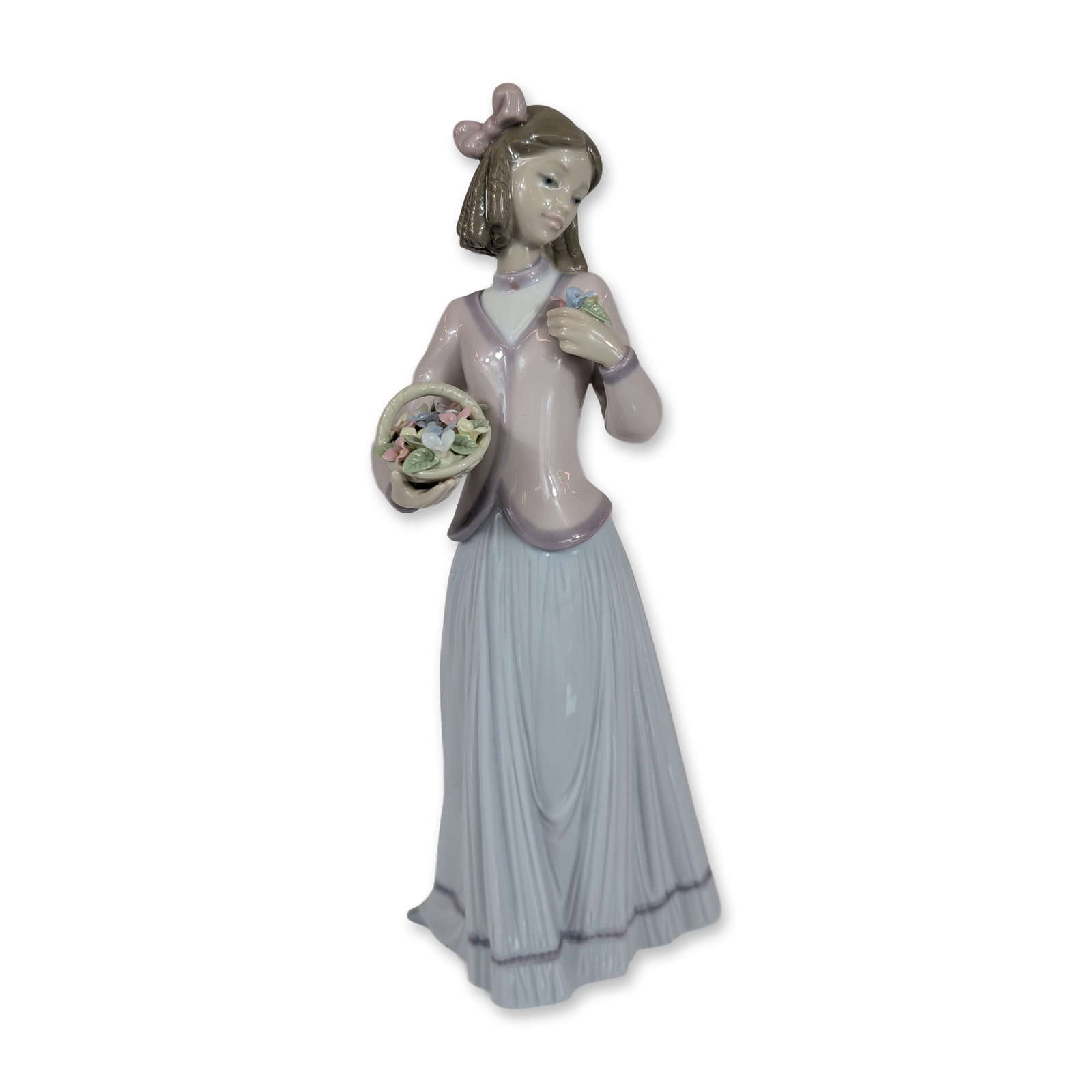 Lladro Porcelain Figurine, Innocence in Bloom 1007644: This 1996 Collectors Society issue depicts a young girl in a mauve bodice with a white collar and a pale blue pleated skirt featuring purple trim. The figure holds a small basket of multicolored flowe