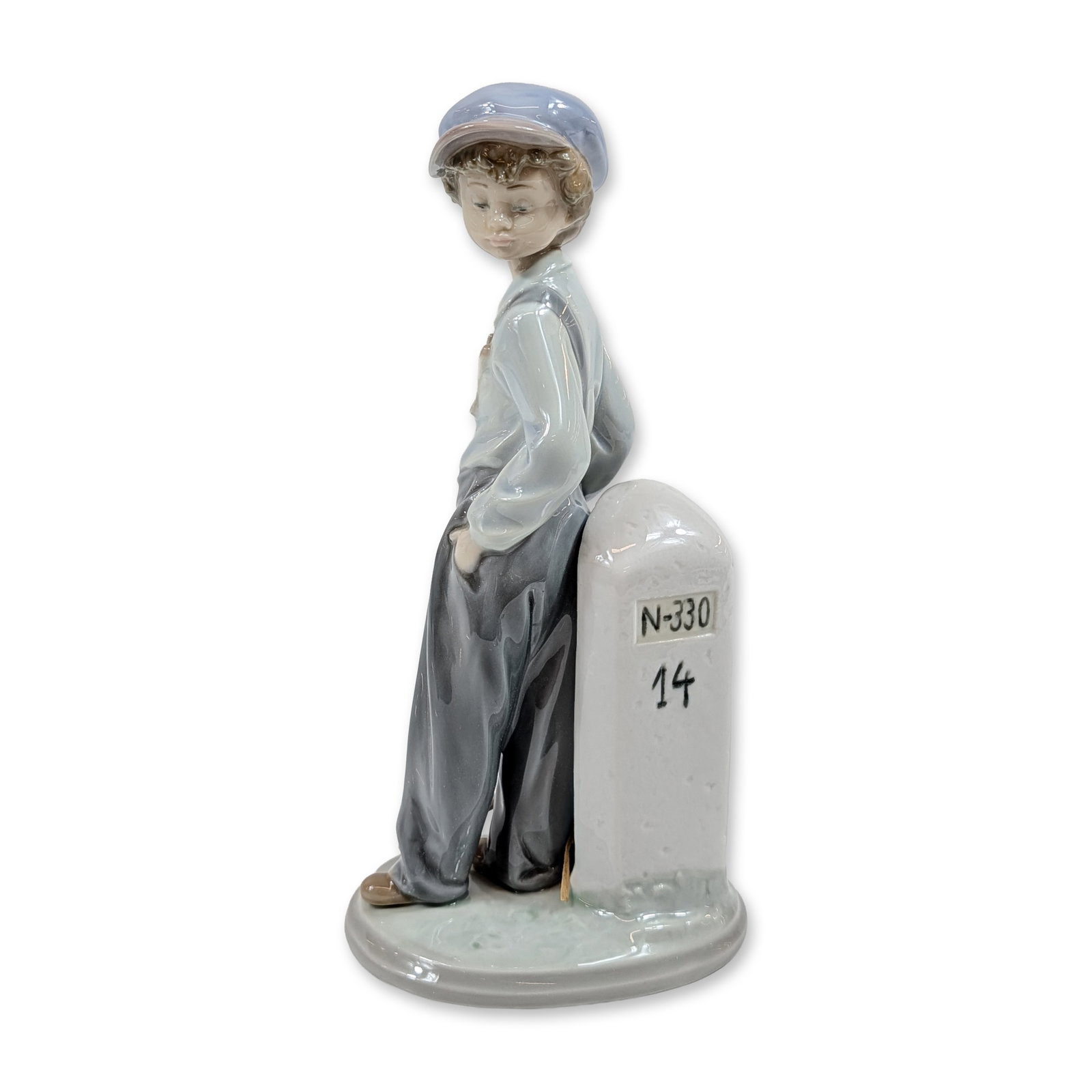 Lladro The Wanderer Porcelain Figurine 5400: Lladro. The Wanderer porcelain figurine in glazed finish, model number 5400. The piece depicts a young boy in a blue cap, light blue shirt, and gray trousers leaning against a white milestone inscribe