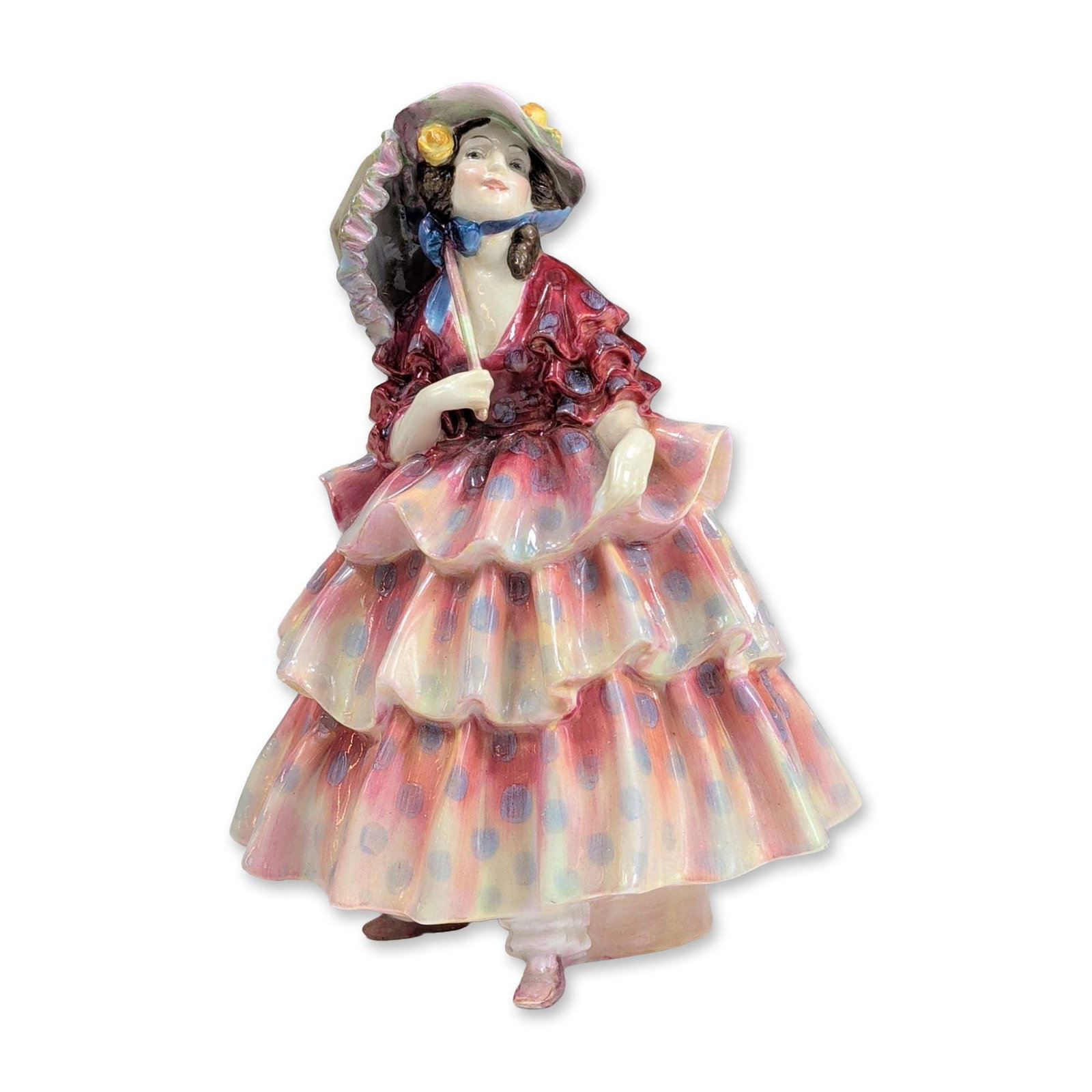 Royal Doulton Porcelain Figurine, The Hinged Parasol HN1578: The figure features an iridescent luster glaze with pink and yellow tones and blue polka dots. The figure is modeled in a tiered ruffled gown and floral bonnet, holding a parasol handle. Underside bea