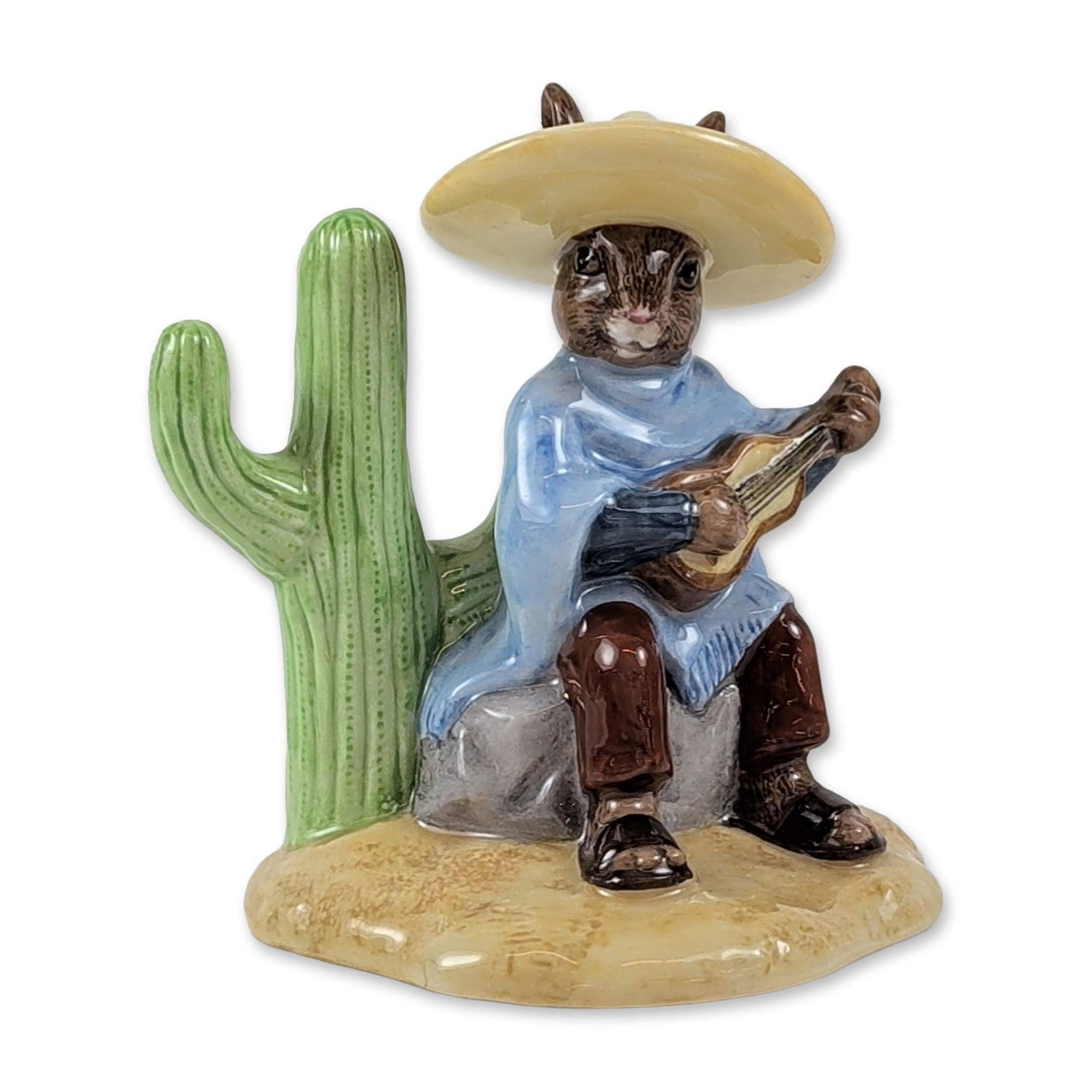 Royal Doulton Mexican Bunnykins DB316 Figurine: Royal Doulton Bunnykins series Mexican Bunnykins figurine, model DB 316. Hand-painted glazed ceramic figure depicting a rabbit in a sombrero and blue sweater seated on a rock playing a stringed instru