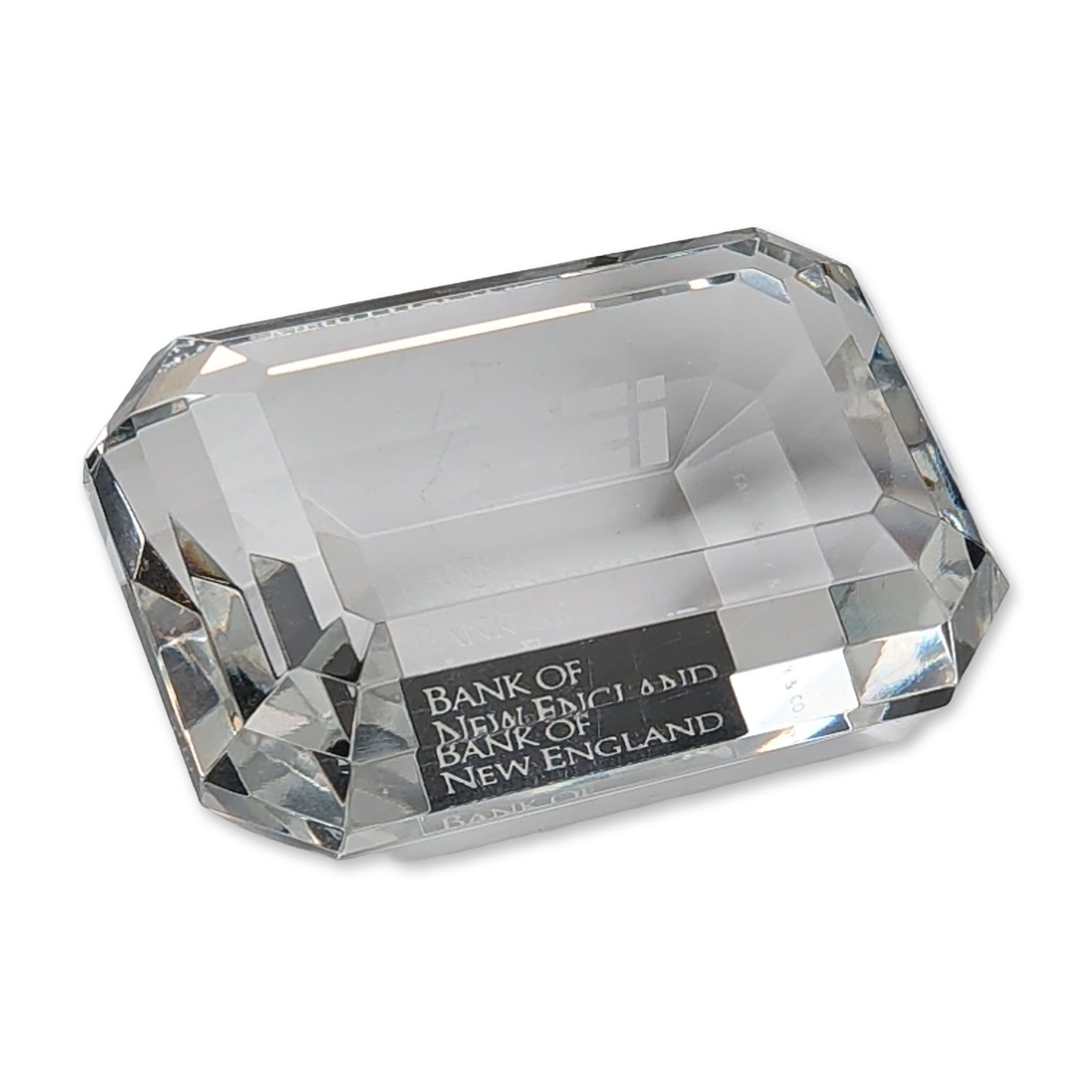 Tiffany and Co Crystal Emerald Cut Bank of New England Paperweight: Tiffany and Co. commemorative paperweight in clear lead crystal, expertly fashioned in a faceted emerald-cut gemstone form. The piece features a broad flat table with step-cut crown facets and a deep 