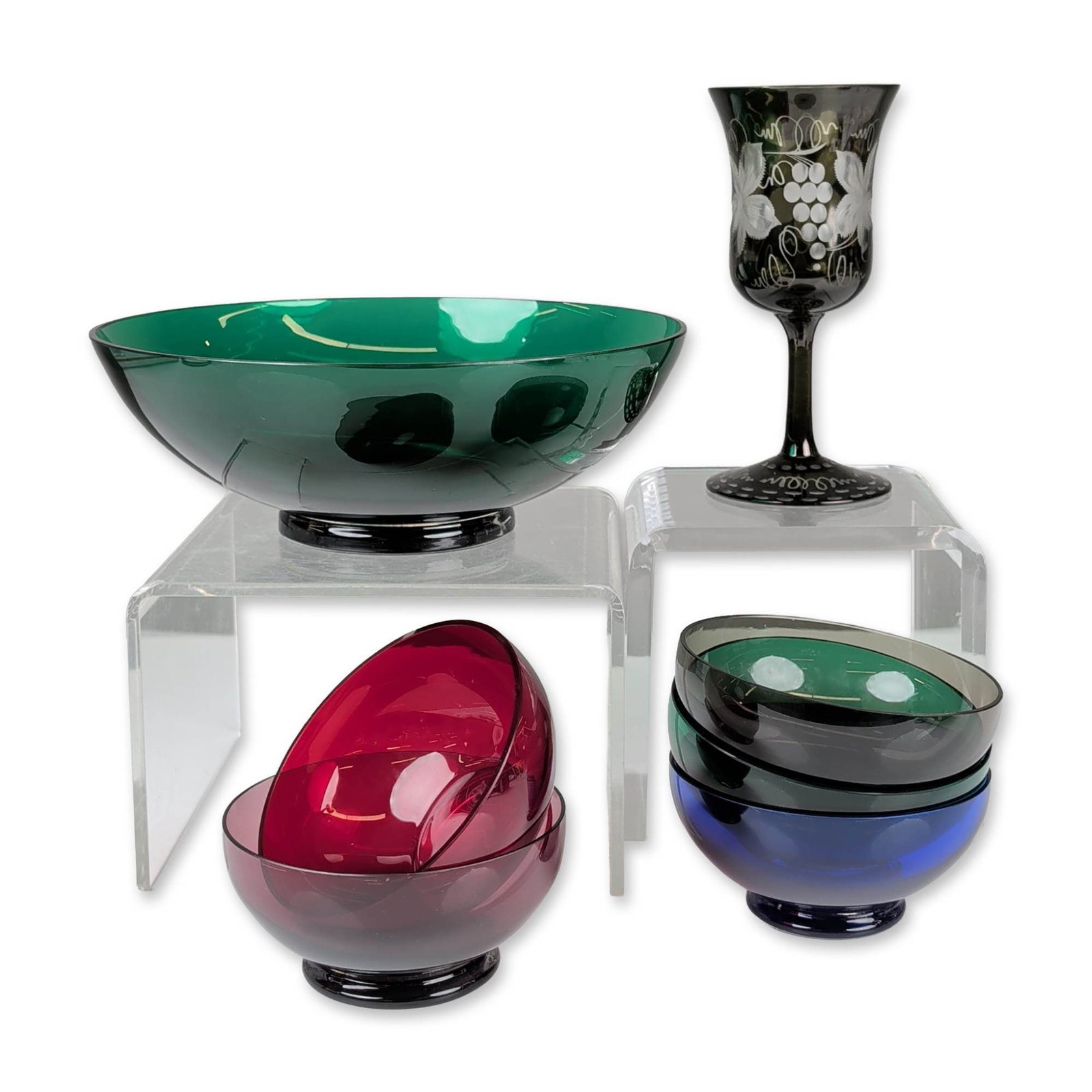 7pc Mid-Century Modern Multi-Colored Art Glass Bowls and Goblet: A seven-piece mid-century modern art glass collection, comprising a large emerald green centerpiece bowl, five individual bowls, and an olive-colored etched goblet. Each blown glass bowl features a he