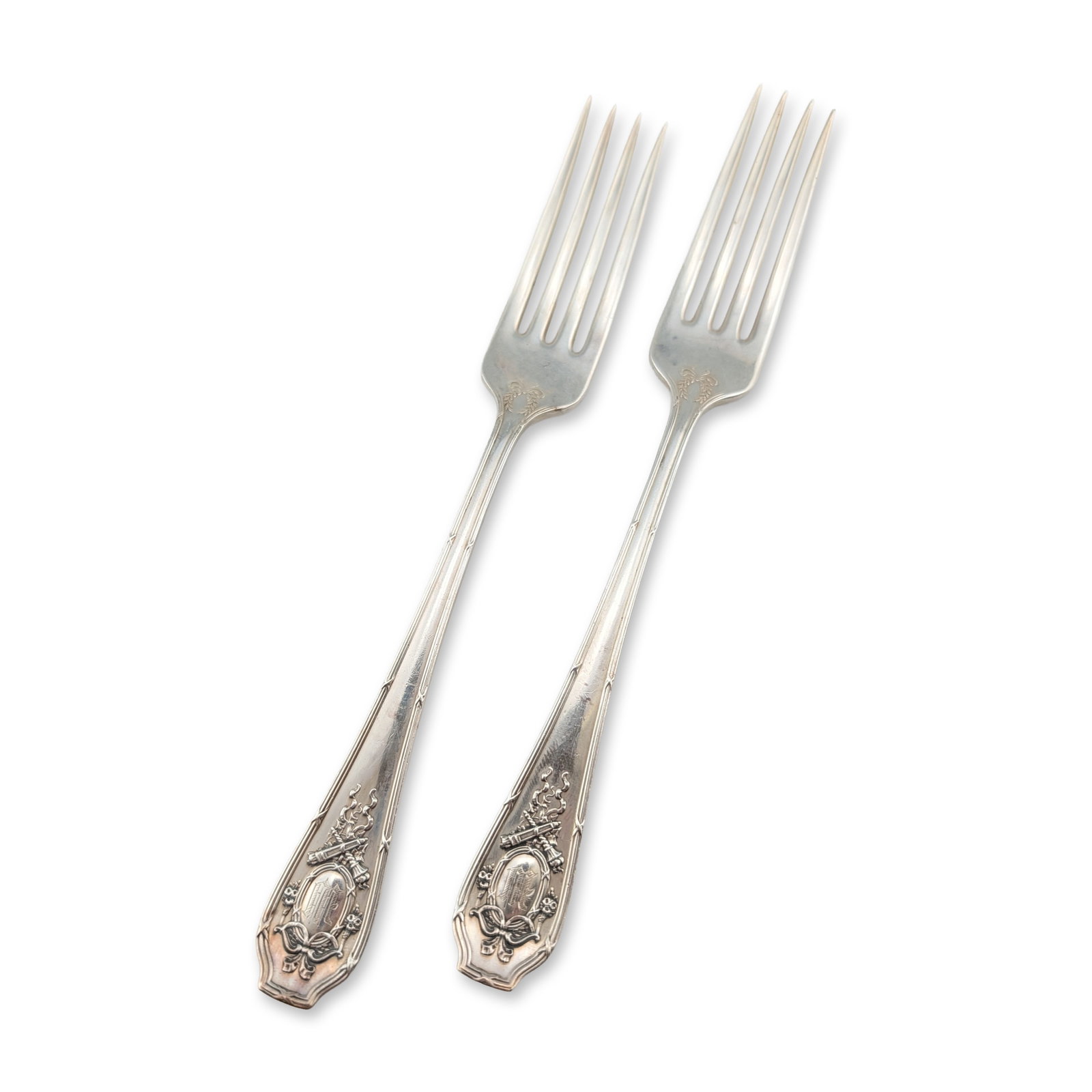 Pair of Wallace Sterling Silver Forks: R. Wallace and Sons Manufacturing Company. Pair of sterling silver forks featuring neoclassical motifs of ribbon bows, floral garlands, and crossed torches. Handles center on an oval cartouche engrave