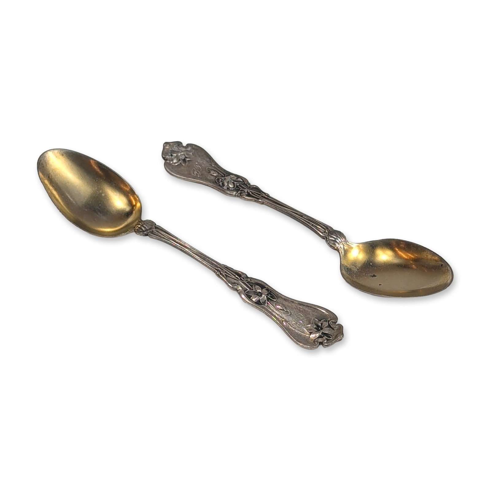 Pair of Whiting Sterling Silver Demitasse Spoons: Sterling silver spoons with gold-washed vermeil bowls. The handles feature an ornate floral pattern in relief. Each piece is marked on the reverse with hallmarks alongside the STERLING designation. Le
