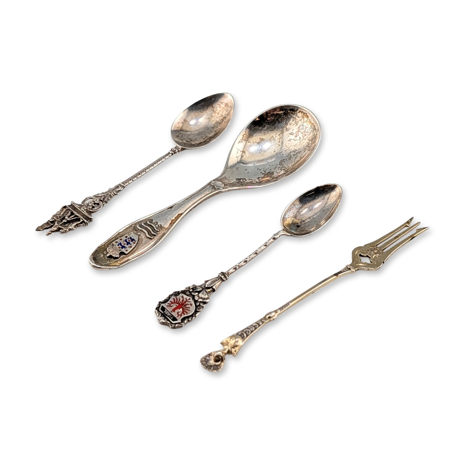 4pc Continental Silver Souvenir Spoons and Fork: This grouping of silver items includes three spoons and a fork, each with a distinct decorative terminal. Designs on the spoons depict the Danish coat of arms, the Venetian Bell Ringers with the word 