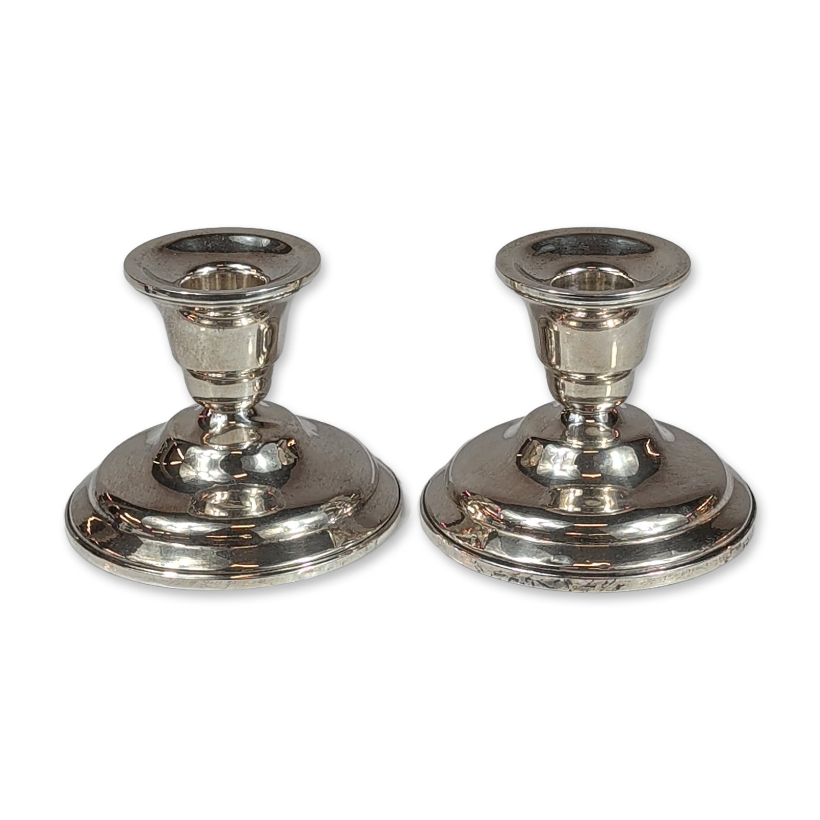 Pair of Shreve, Crump & Low Co Weighted Sterling Silver Candlesticks: Shreve, Crump and Low Co. A pair of weighted sterling silver candlesticks, featuring a low-profile form with circular stepped bases and plain cylindrical cups. The underside of each base is stamped wi