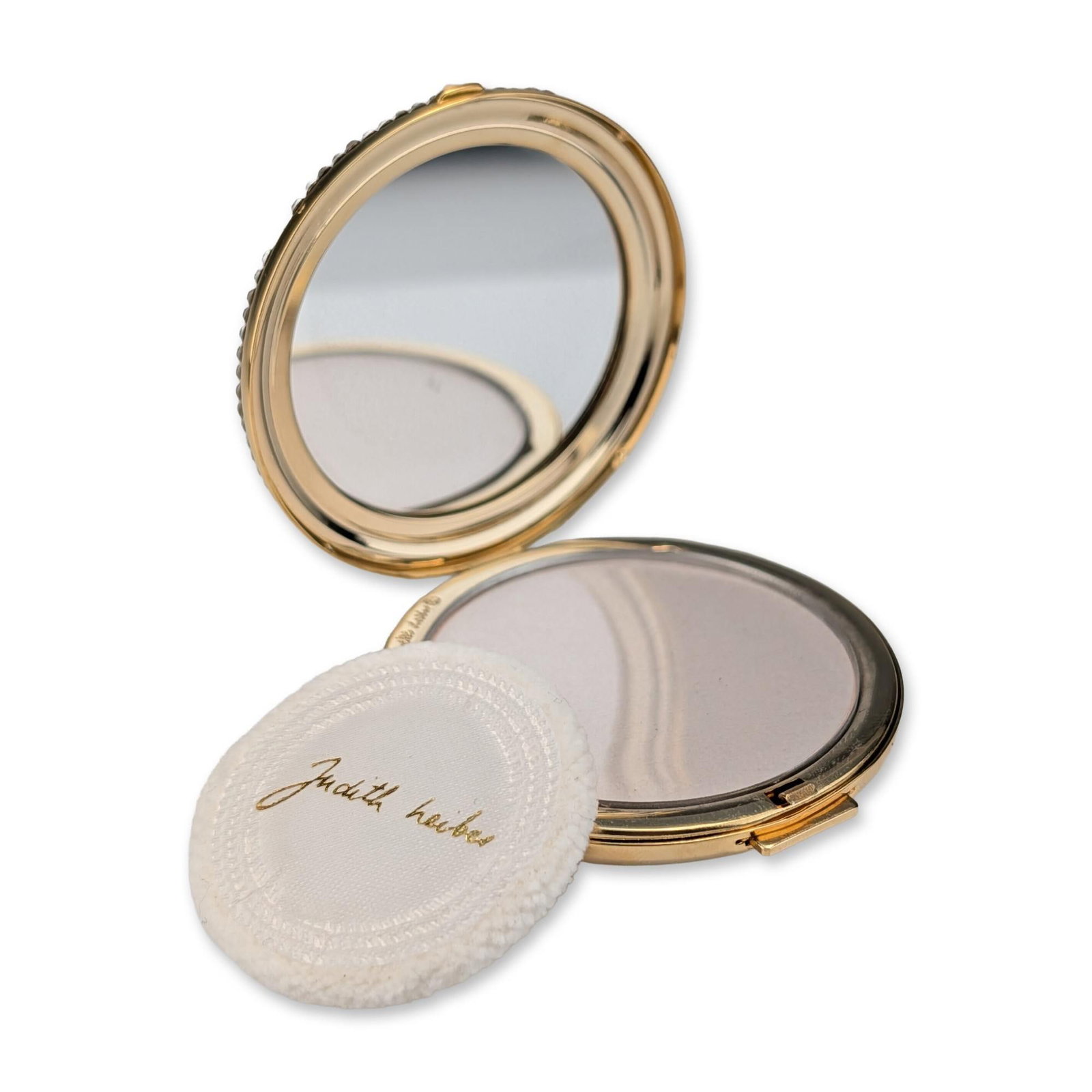 Judith Leiber Crystal and Pearl Trellis Compact: Judith Leiber circular powder compact in gold-tone metal, featuring a decorative lid with a raised trellis pattern set with clear rhinestones and white faux pearls at each intersection. The piece is c