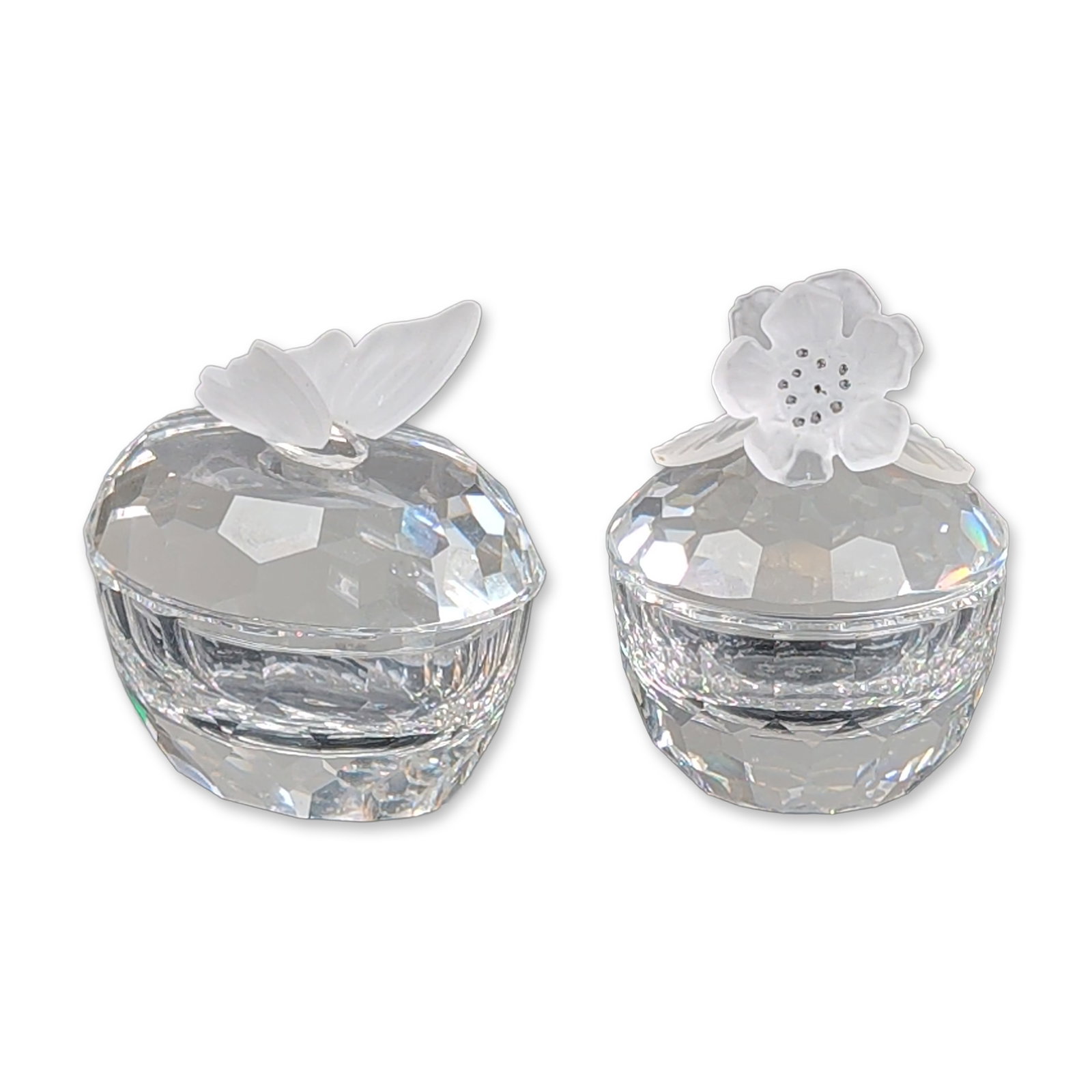 2pc Swarovski Silver Crystal Keepsake Boxes, Treasure Heart Butterfly & Flower: Two miniature keepsake boxes in faceted clear lead crystal, each featuring a separate lid topped with a frosted crystal finial. One lid is surmounted by a butterfly and the other by an anemone flower.
