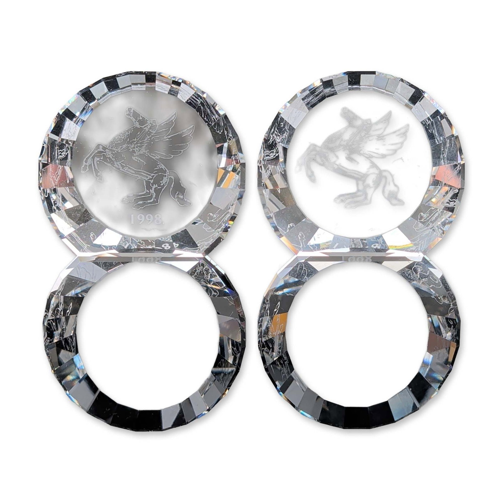 Pair of D. Swarovski Crystal Colors Crystal 1998 Pegasus Paperweights: A pair of faceted paperweights in clear crystal, each featuring an internal etched motif of a rearing Pegasus winged horse. Each circular piece is designed with a flat reverse and a domed obverse