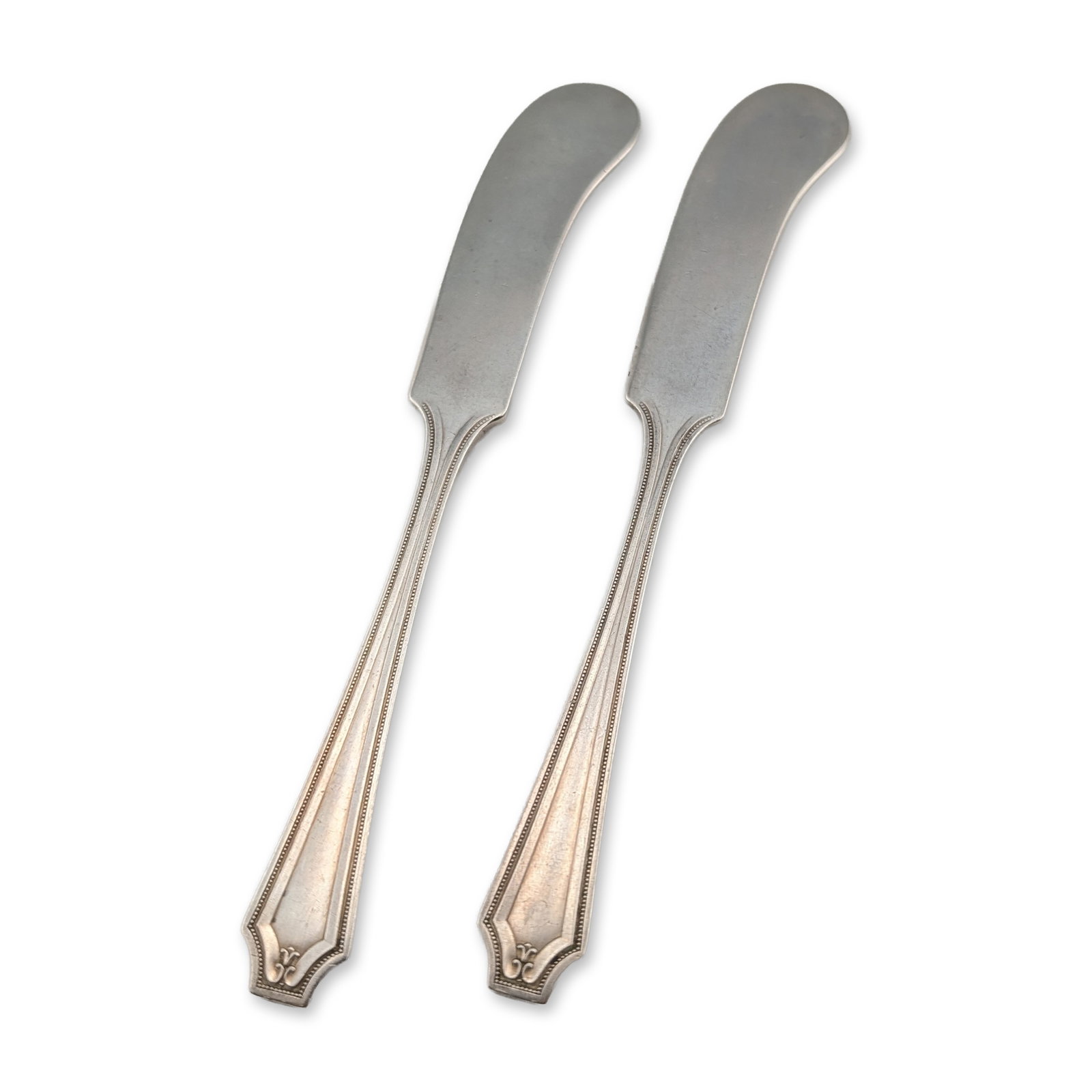 Pair of Whiting King Albert Sterling Butter Spreaders: Whiting Manufacturing Company. Pair of flat-handle butter spreaders in the King Albert pattern, crafted in sterling silver. The handles feature an Art Deco design with clipped corners, faceted edges, 