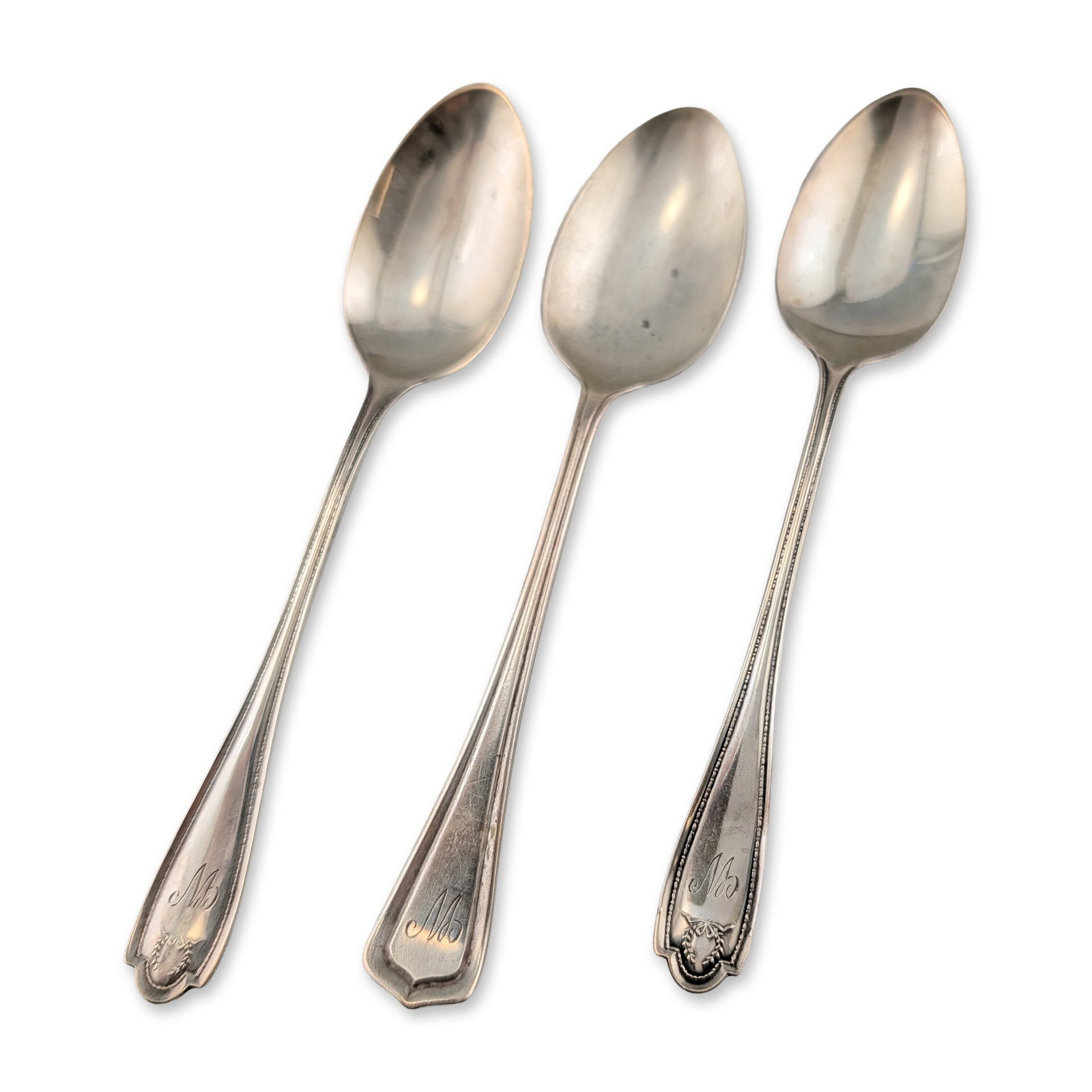 Lunt Silversmiths Sterling Silver Teaspoons, Trio: Trio of sterling silver teaspoons, including one example is characterized by a clipped-corner handle tip. The remaining two spoons feature rounded lobed handle tips with reeded borders and laurel wrea