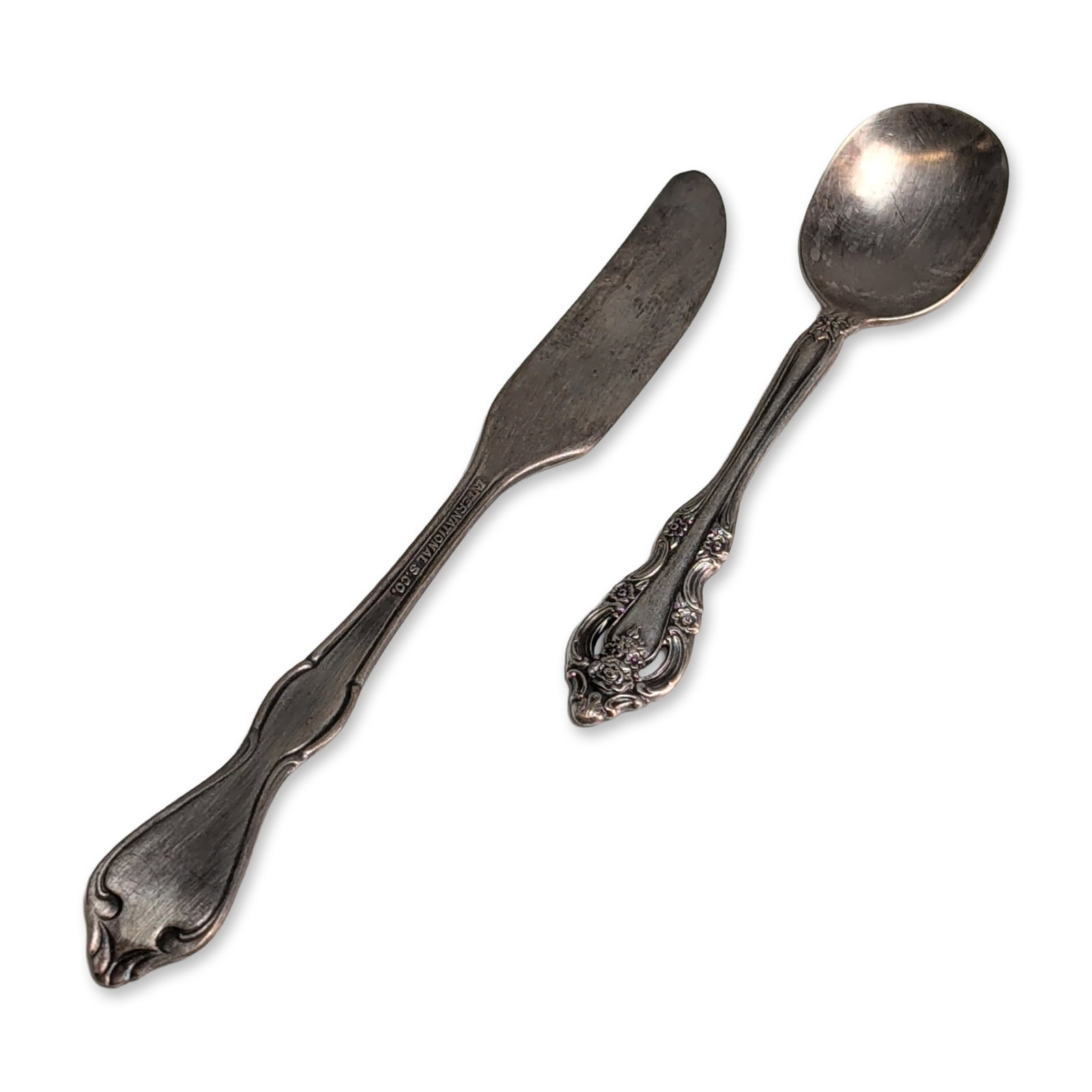Two Oneida and International Silver-Plated Flatware Pieces: One Oneida Community silver-plated spoon in the Coronation pattern, introduced in 1936, featuring a pierced handle terminal with floral and scrollwork decoration. Marked Community on the reverse of th