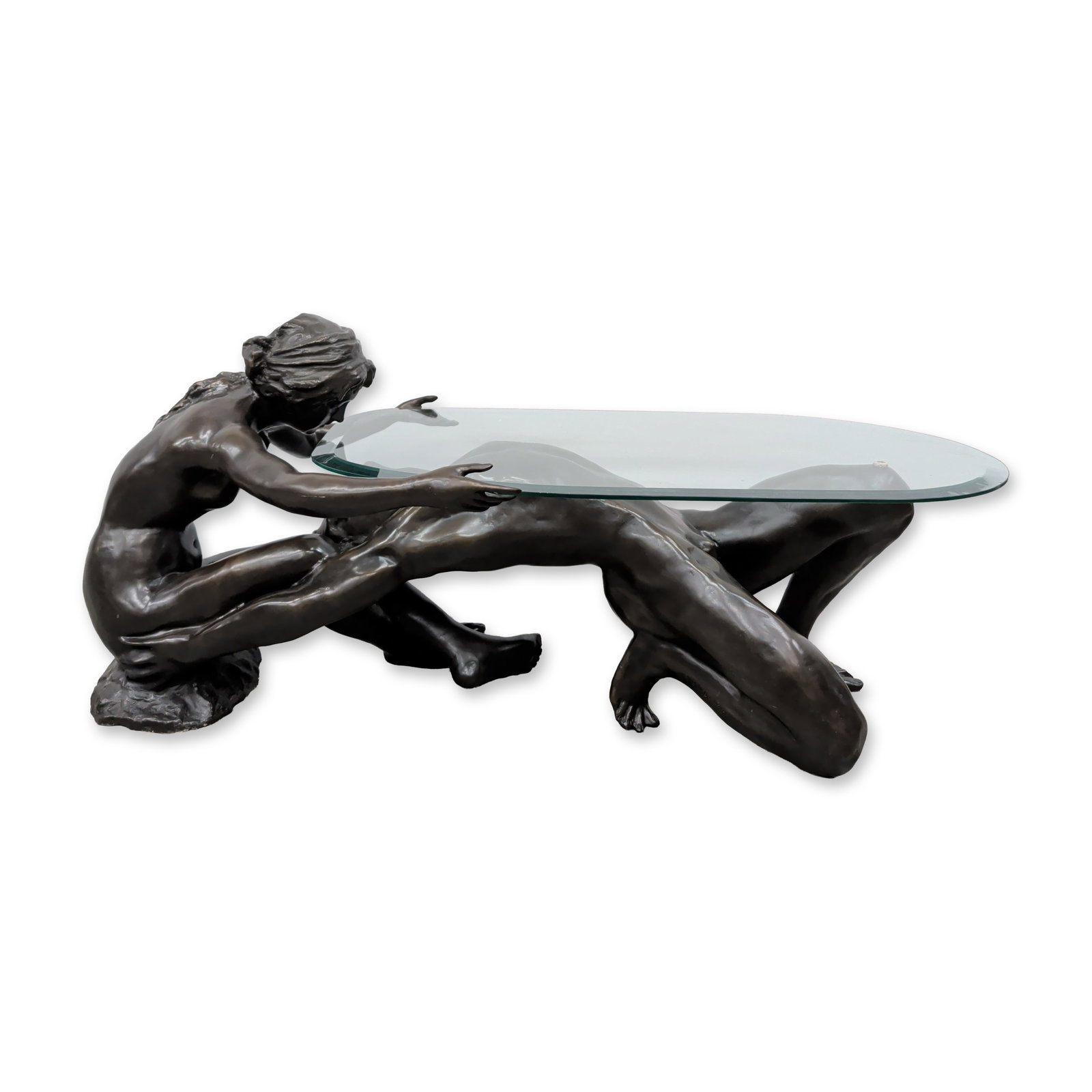 Contemporary Bronze Adam & Eve Figural Glass Coffee Table: Contemporary coffee table featuring a cast bronze base and a clear oval glass top. The sculptural base depicts two nude figures, Adam and Eve, in an intertwined and dynamic pose. The male figure is po
