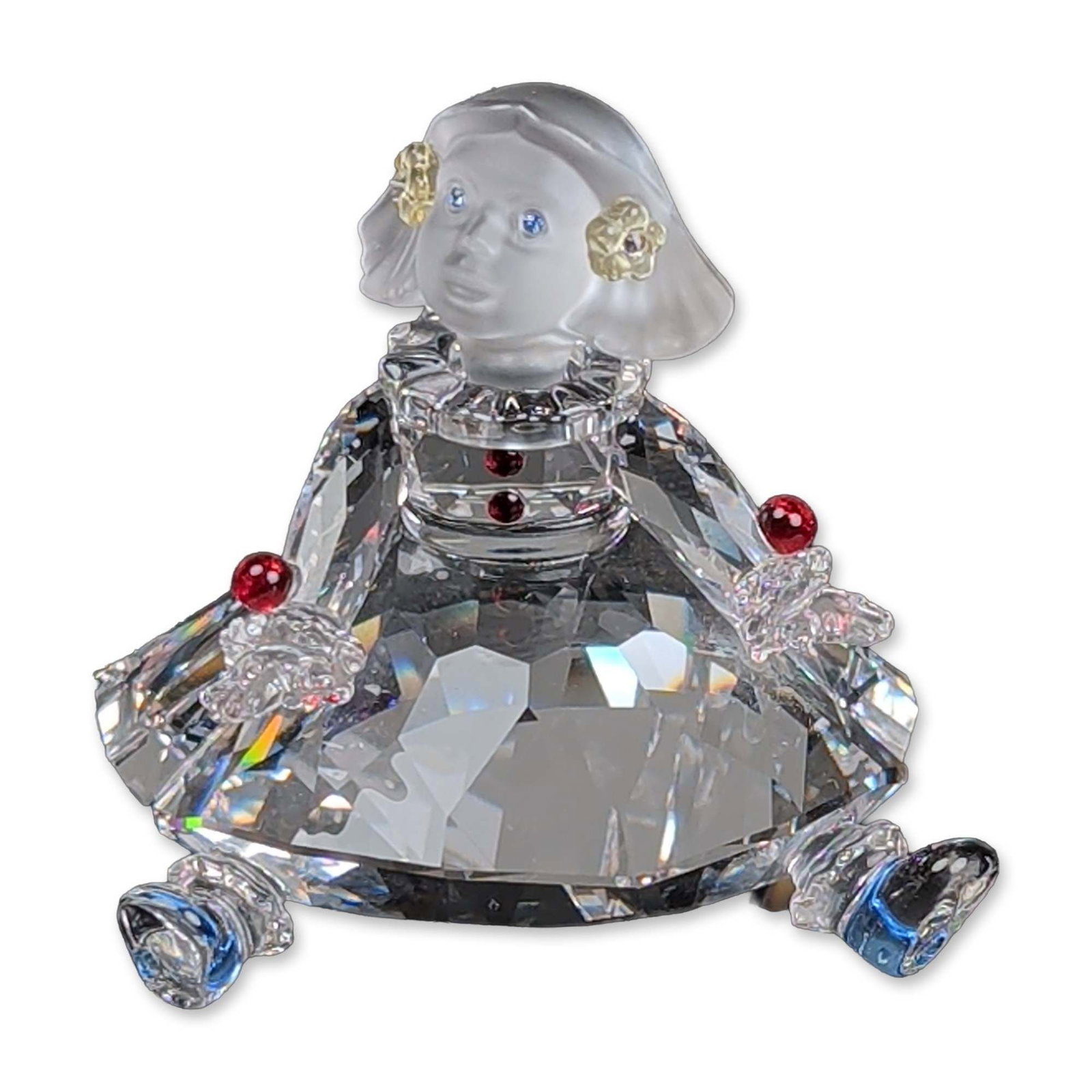 Swarovski Crystal Figurine, Doll: Part of the Cheerful Times figurines this piece is in faceted and frosted lead crystal. The figure features a frosted crystal head with blue crystal eyes and yellow crystal hair ornaments. Adorned wit
