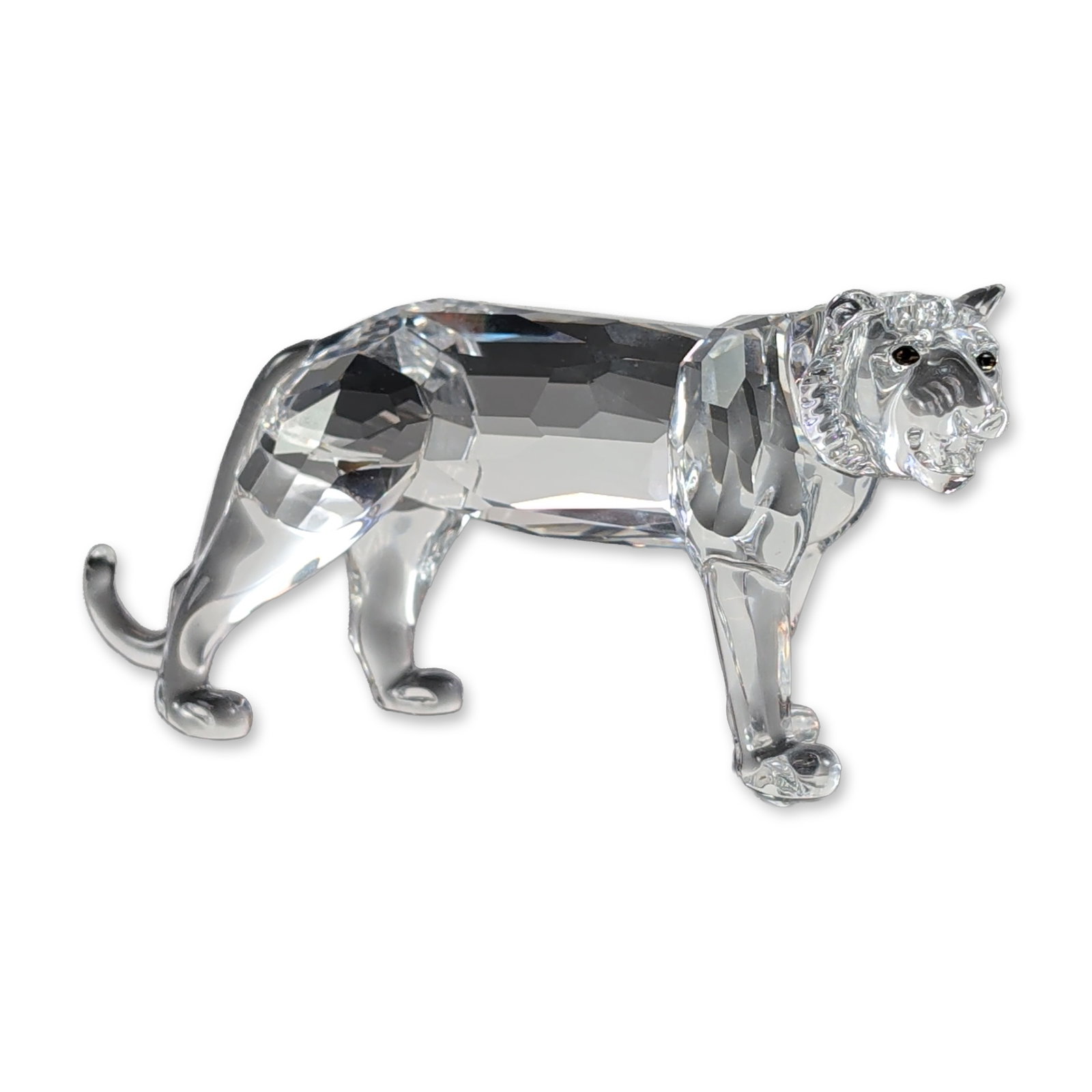 Swarovski Silver Crystal Tiger Figurine: Swarovski. Tiger figurine in clear faceted lead crystal, featuring a prowling pose and dark crystal eyes. Marked with an acid-etched swan maker mark on the underside of a back paw. Includes the origin