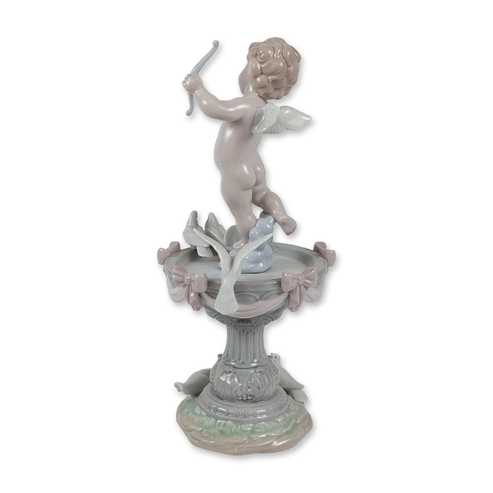 Lladro Spanish Porcelain Fountain of Love Figurine: Lladro (Spanish, 20th century). Fountain of Love, model number 6458, glazed porcelain figurine. This piece depicts a winged cherub holding a light blue bow, positioned beside a classical birdbath deco