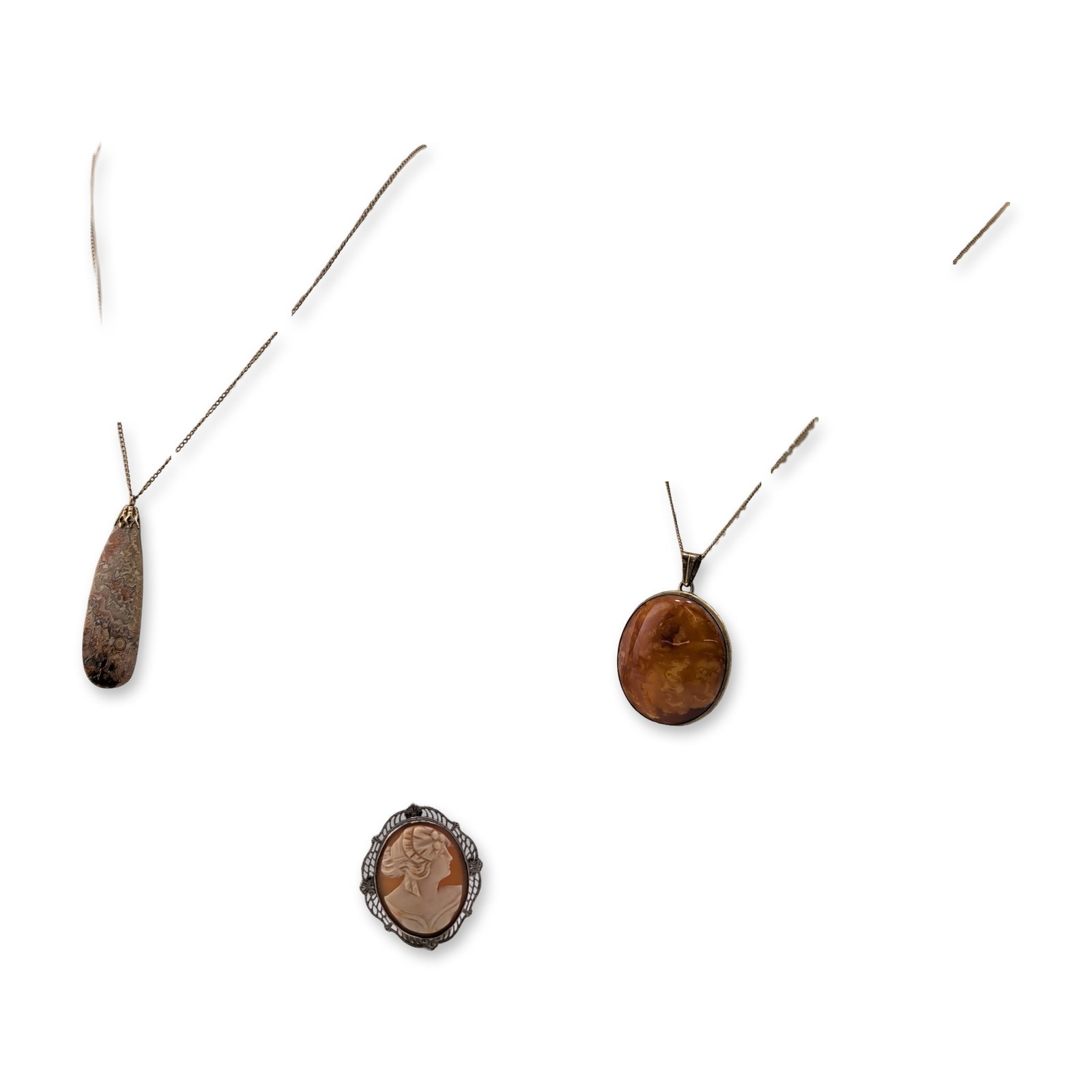 3pc Vintage Agate, Amber, and Cameo Gold-Plated Jewelry: Trio of vintage jewelry pieces comprising two pendant necklaces and a convertible shell cameo brooch. The first necklace features a large circular translucent honey-colored amber cabochon in a