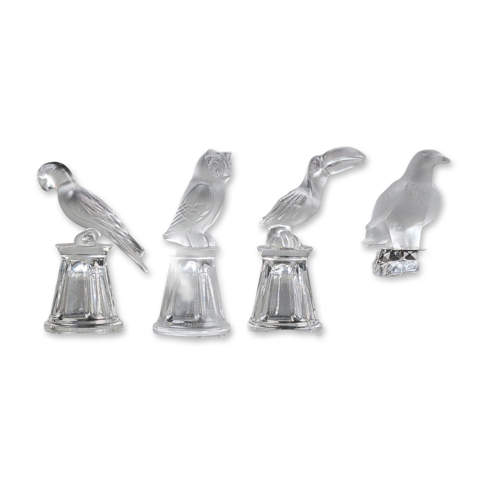 4pc Crystal Colors Bird Thimbles: Crystal Colors. Set of four thimbles in frosted and clear glass, each featuring a distinct avian subject. The collection includes a parrot, owl, and toucan on fluted clear glass bases, and a hawk or f