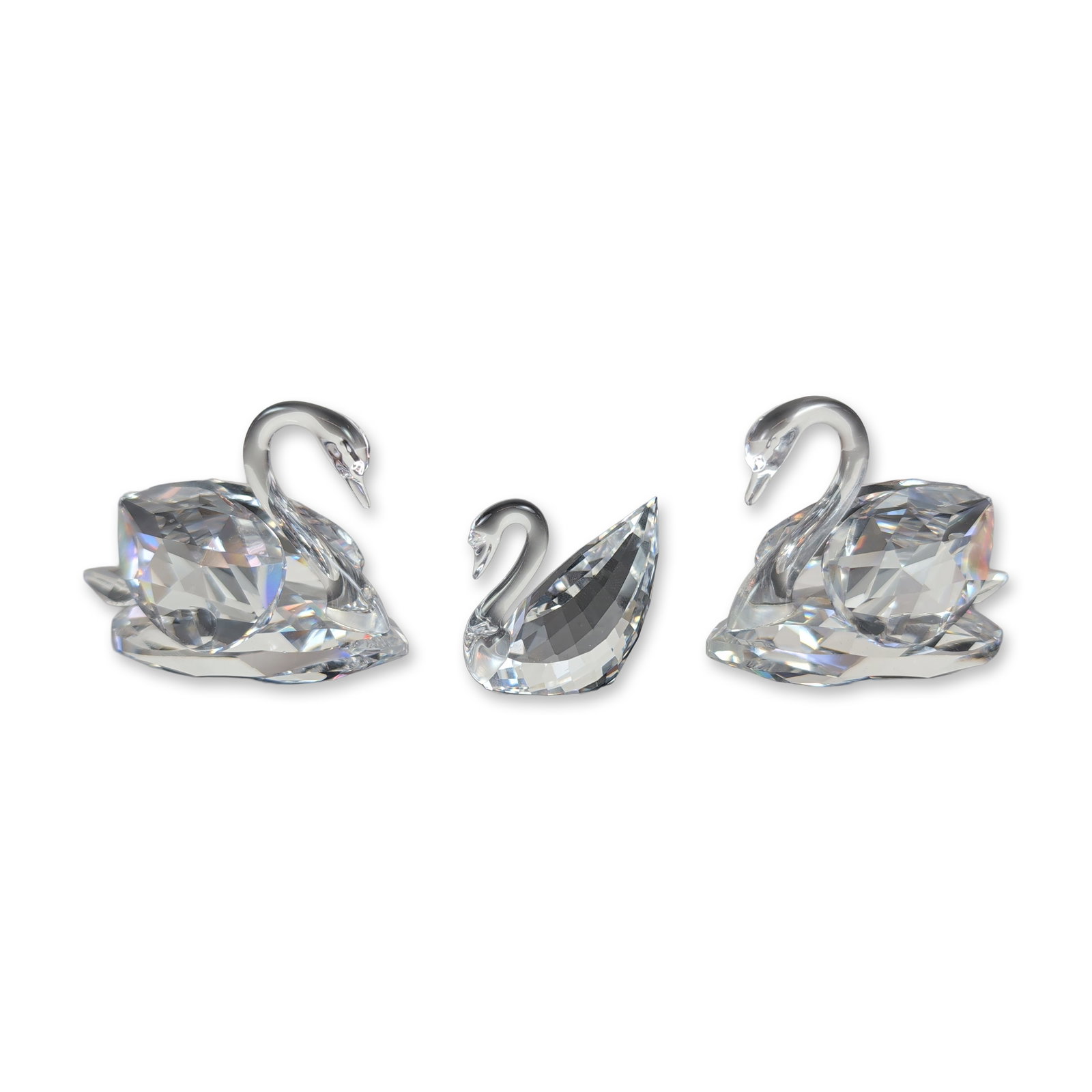 Trio of Swarovski Faceted Crystal Swan Figurines: Swarovski clear faceted lead crystal set featuring two elegant larger swans and a charming smaller cygnet. Each piece showcases smooth, molded necks and heads paired with bodies adorned in countless p