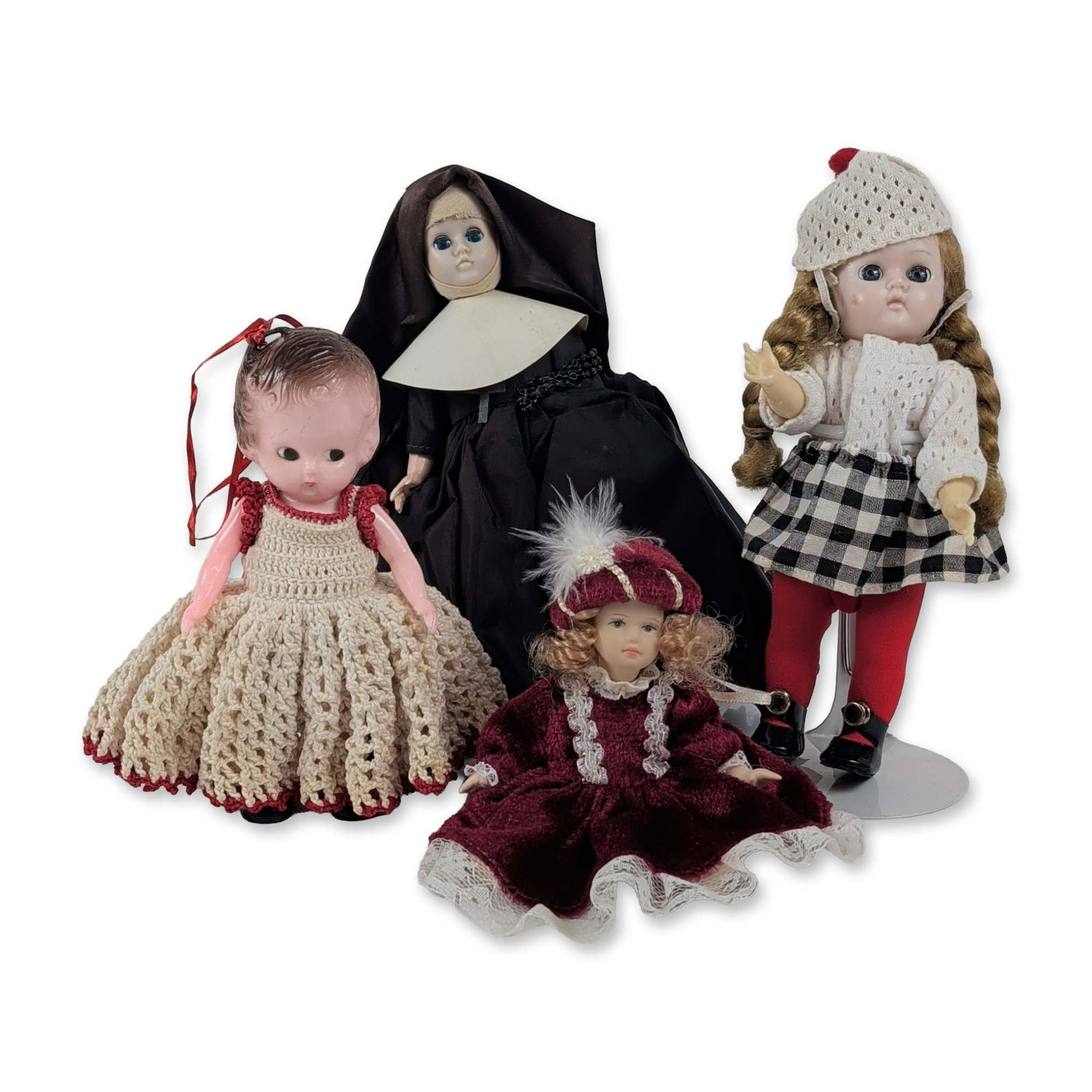 Group of Four Assorted Collector Dolls: Assortment of four collector dolls in varying materials, including porcelain and hard plastic. The group features a doll with plastic head and blonde braids in a winter ensemble with a checkered skirt