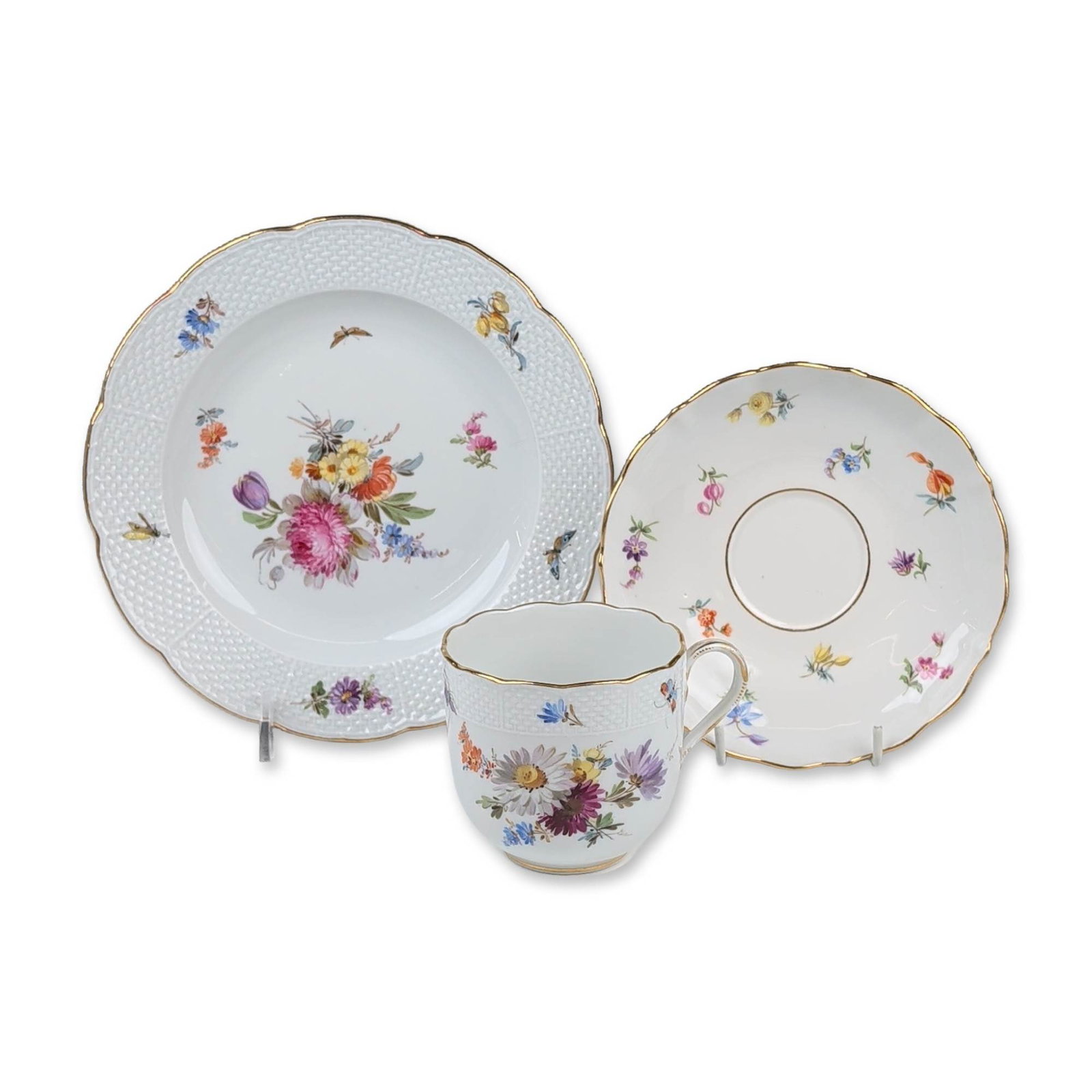 3pc Meissen German Flowers Porcelain Tea Trio: A three-piece Meissen porcelain tea trio, comprising a teacup, saucer, and dessert plate. Each piece is hand-painted in polychrome enamels with Deutsche Blumen floral sprays and scattered insect motif
