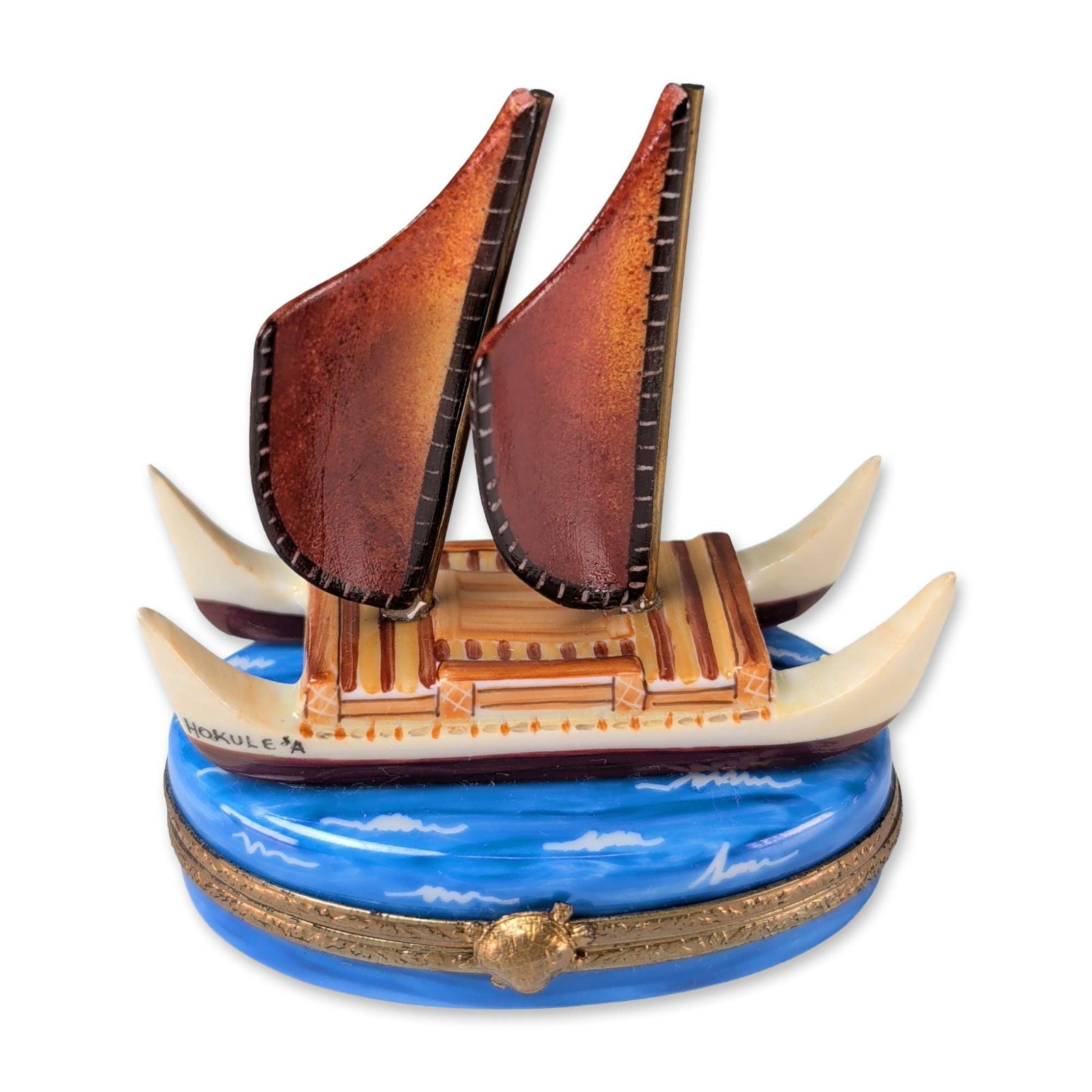 Limoges Hand Painted Hokulea Canoe Porcelain Box: French hand painted porcelain hinged trinket box featuring a sculptural representation of the Hawaiian voyaging canoe Hokulea. The lid depicts a double-hulled vessel with two reddish-brown crab-claw s
